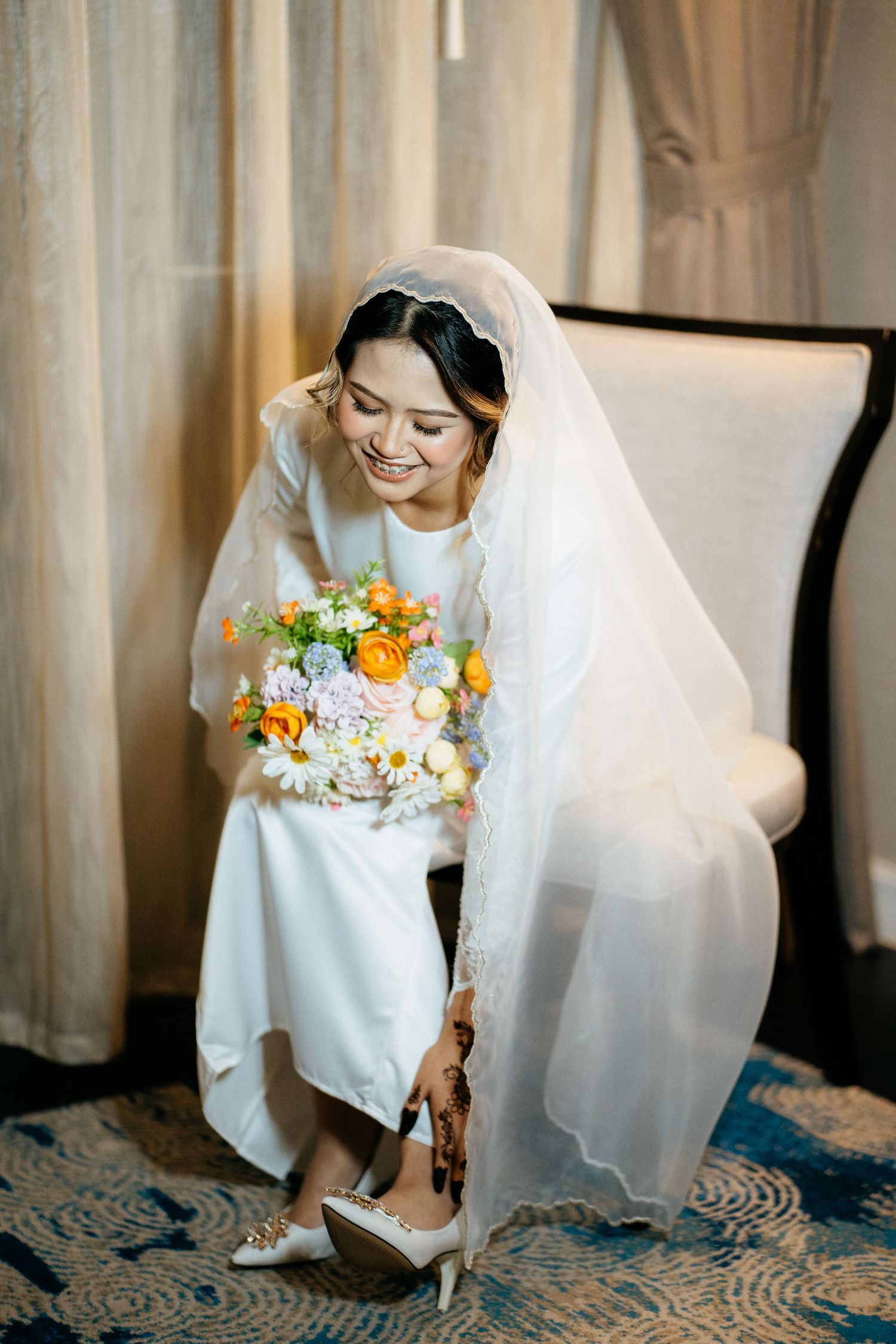 Wedding preparation scene showing bride's shoes and bouquet with white dress and orange and yellow flowers.
