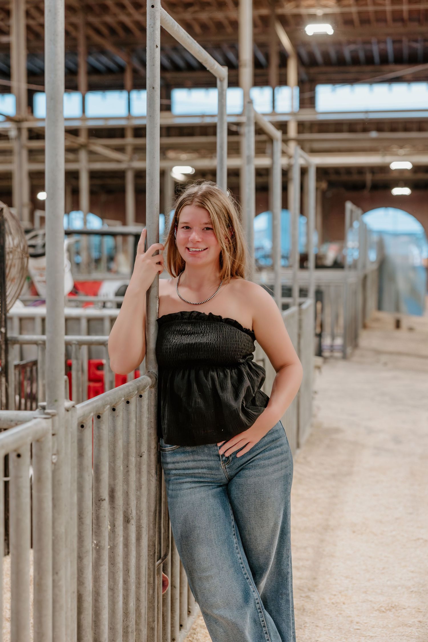 A casual photoshoot inside a rustic barn with wooden stalls and industrial lighting.