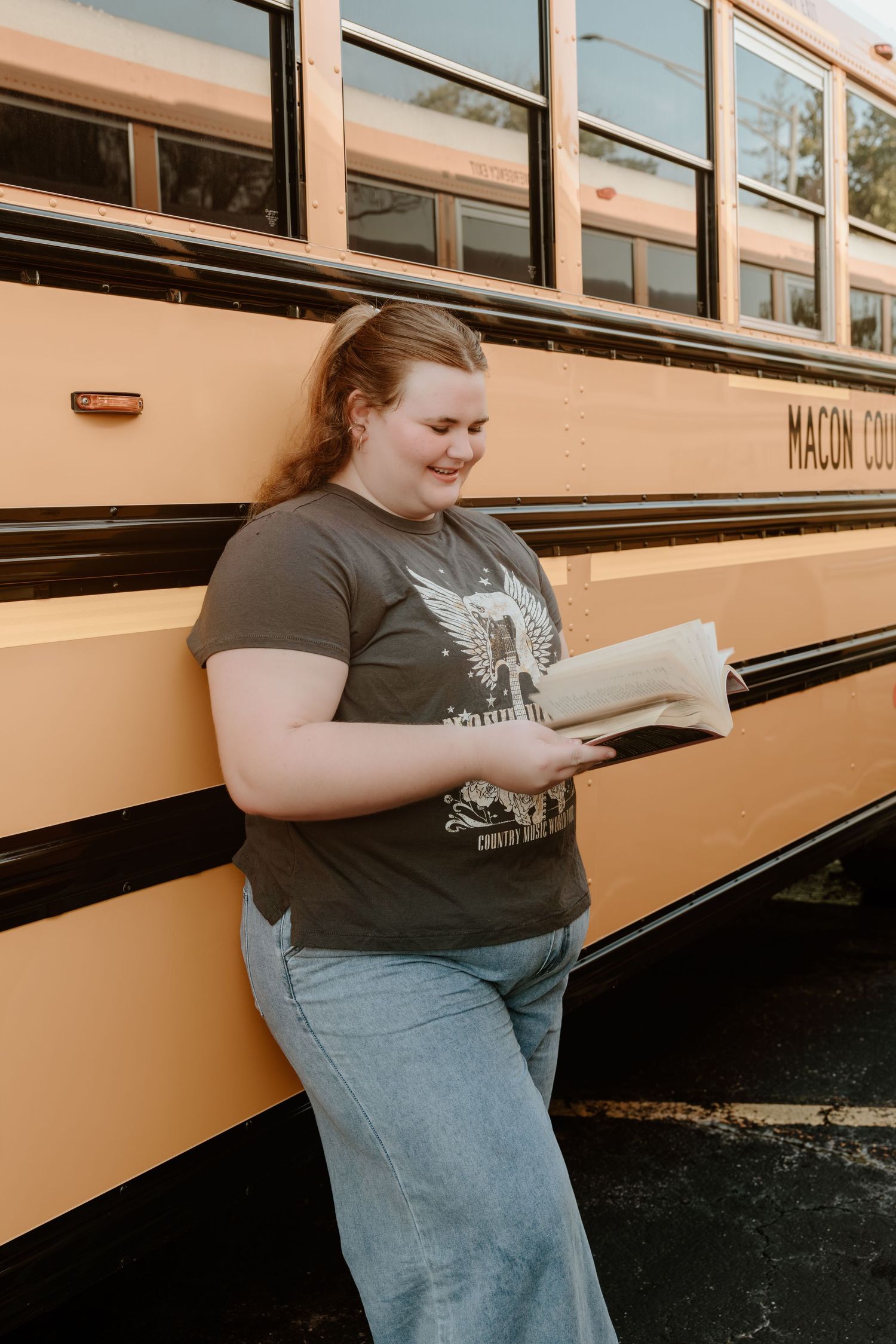 A casual photography session showing different poses while reading beside a classic school bus.