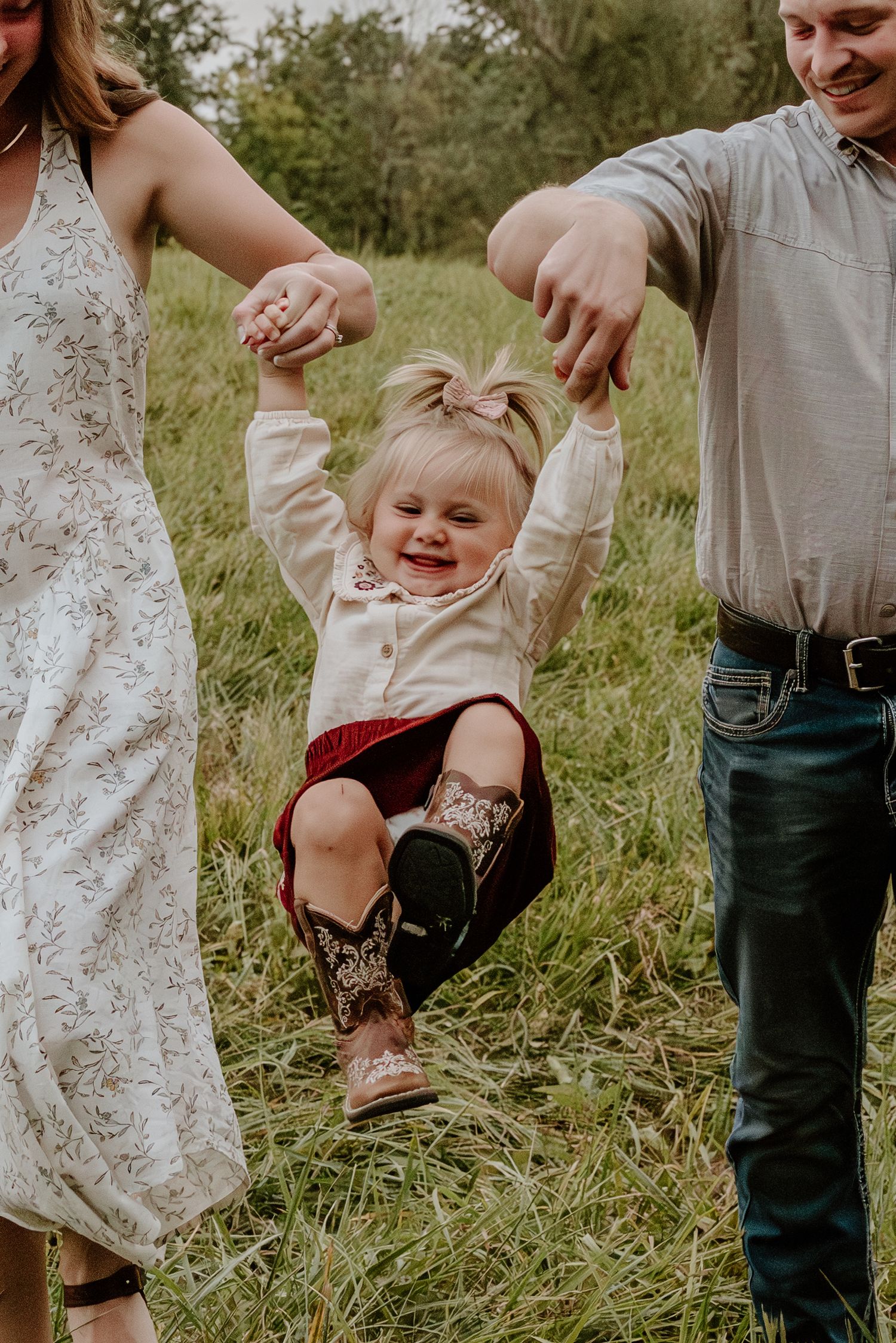A candid moment of a family playing together in a grassy field on a sunny day.