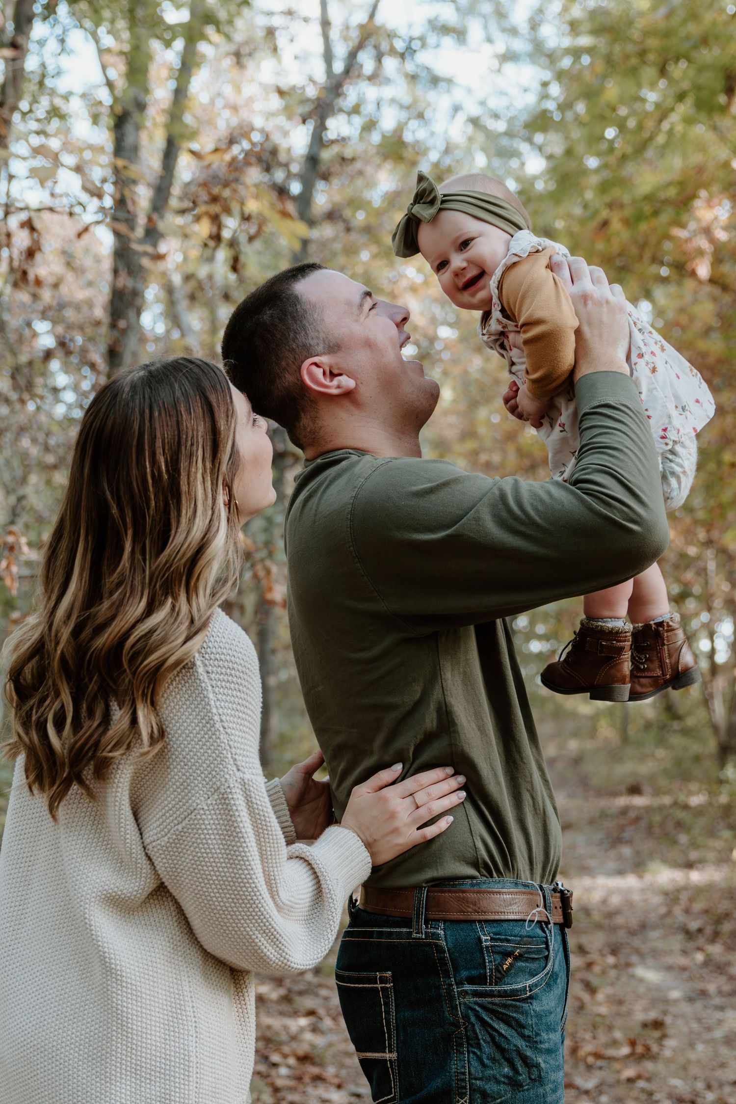 A family shares a joyful moment together on an autumn day in the woods wearing cozy sweaters.