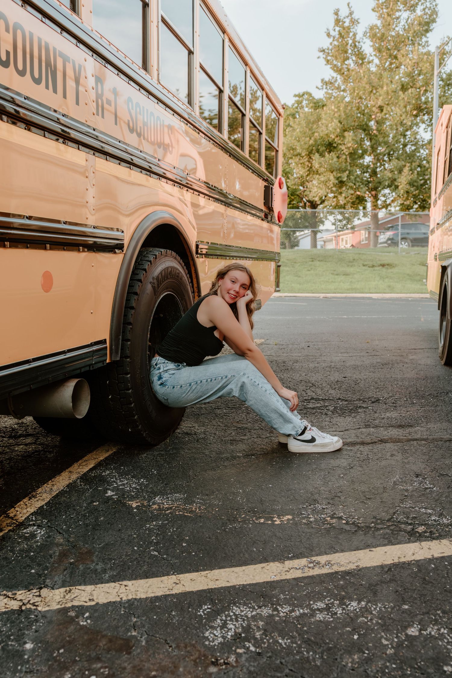 Creative poses shot underneath a parked yellow school bus on asphalt.