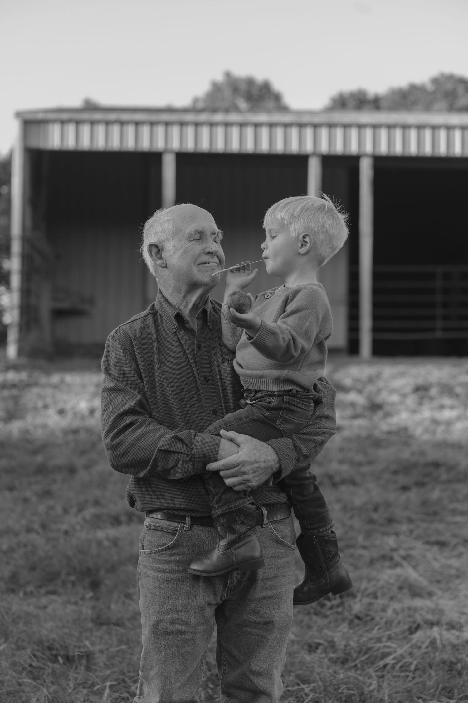 Black and white photo series showing two people embracing in a field with farm buildings visible in background.