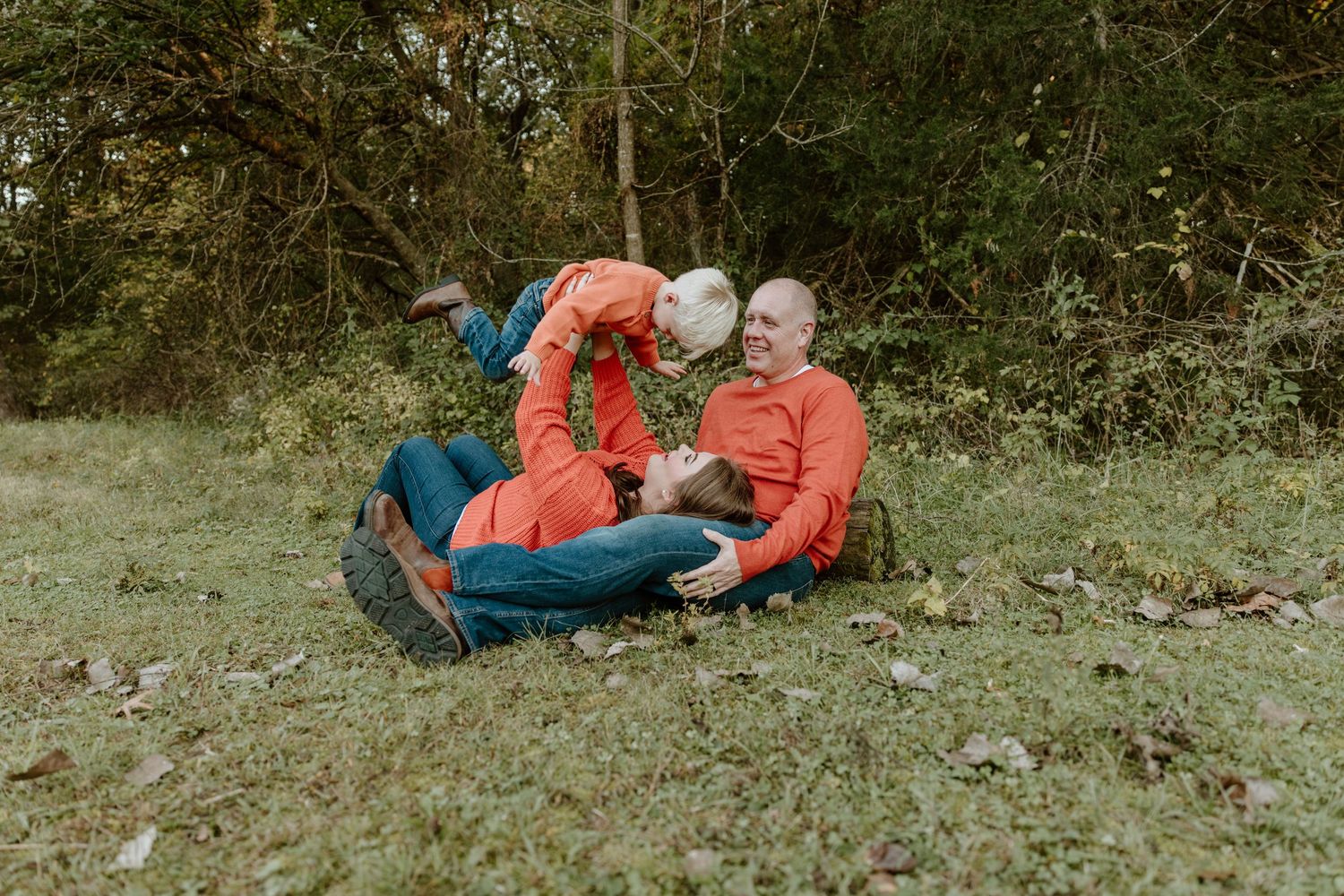 A sequence of four photos showing a couple in orange jackets laying together on grass in autumn.