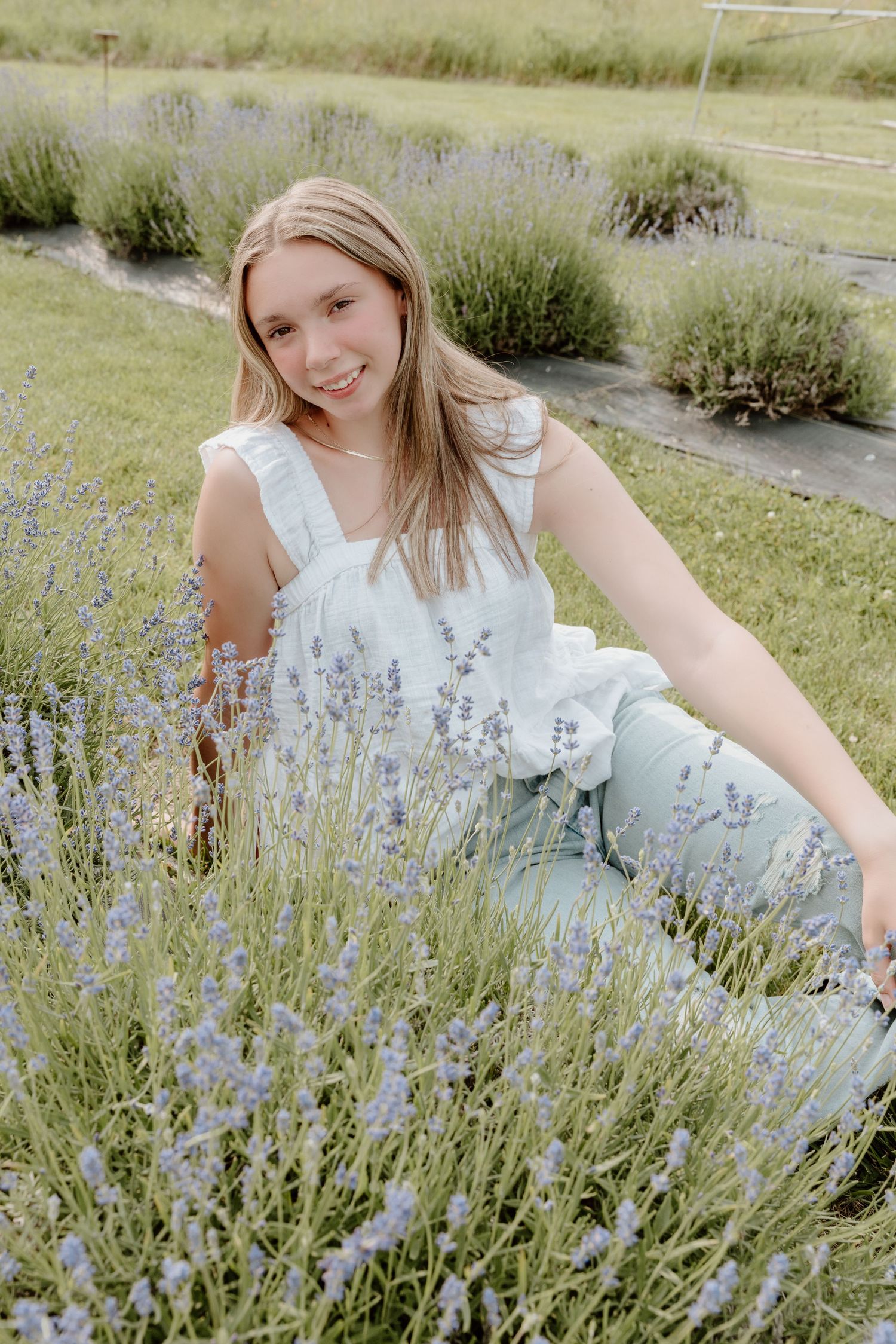 Someone sitting among blooming lavender plants in a garden wearing a white summer dress.