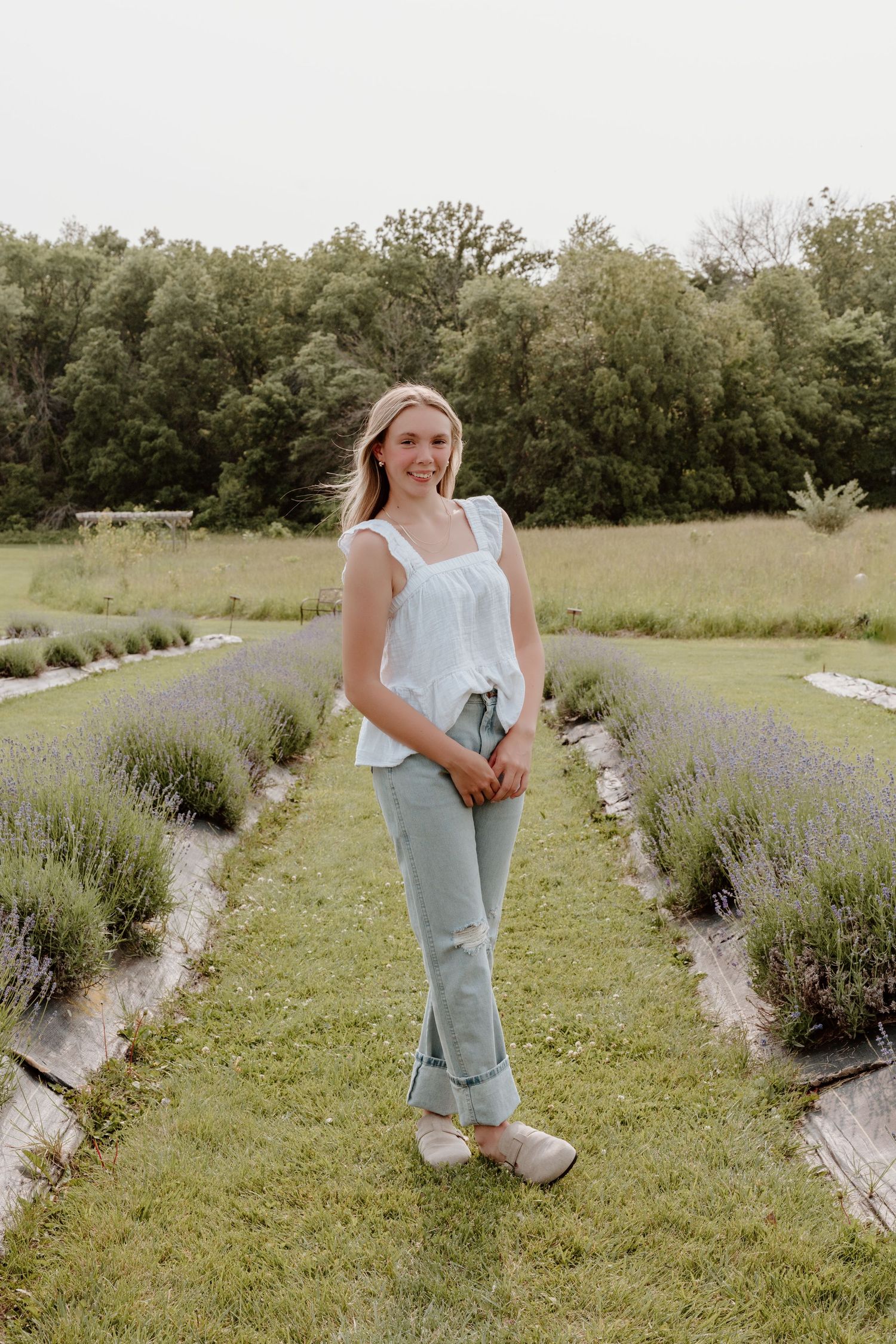 Candid shots in a blooming lavender garden wearing light denim and a white top against natural greenery.