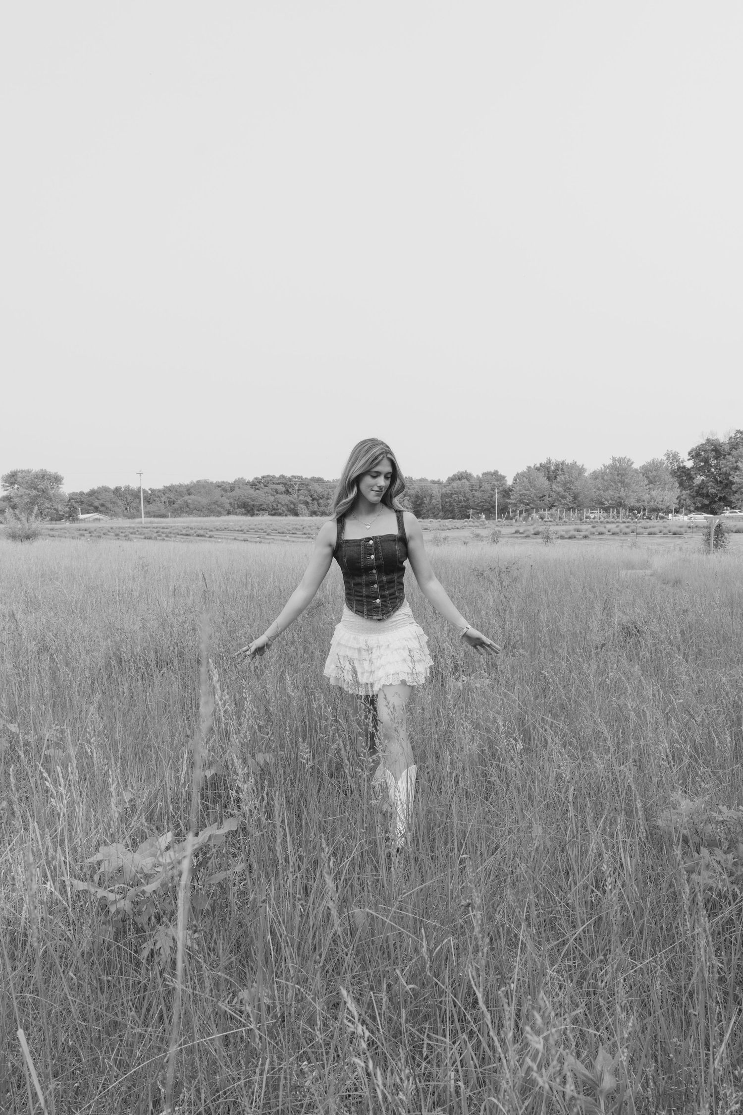 Three black and white photos show someone walking through a tall grass meadow on a sunny summer day.