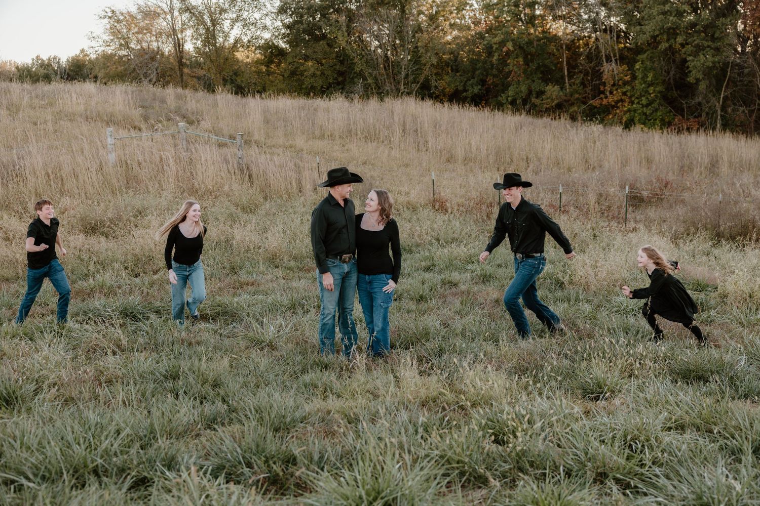 A sequence of people falling down a grassy hill in a playful domino effect on an autumn day.