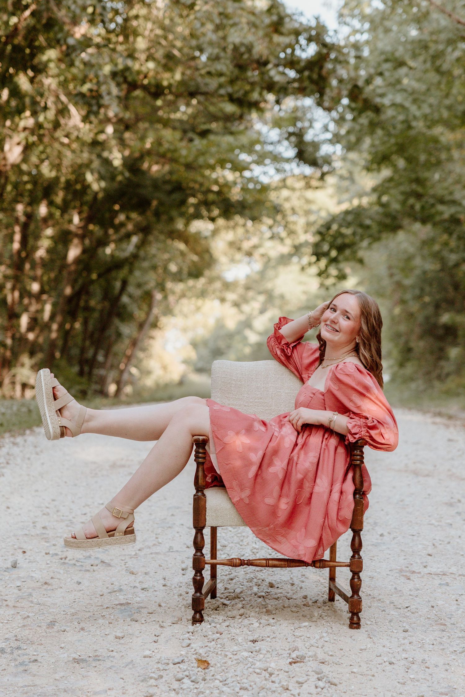 A series of playful poses on a rustic wooden bench in a sunlit outdoor setting wearing a coral-colored dress.