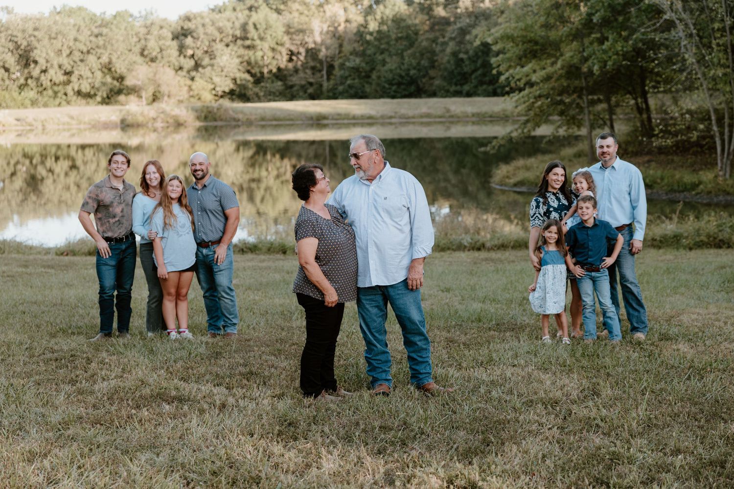 A group of people stand together in a grassy field during golden hour lighting.