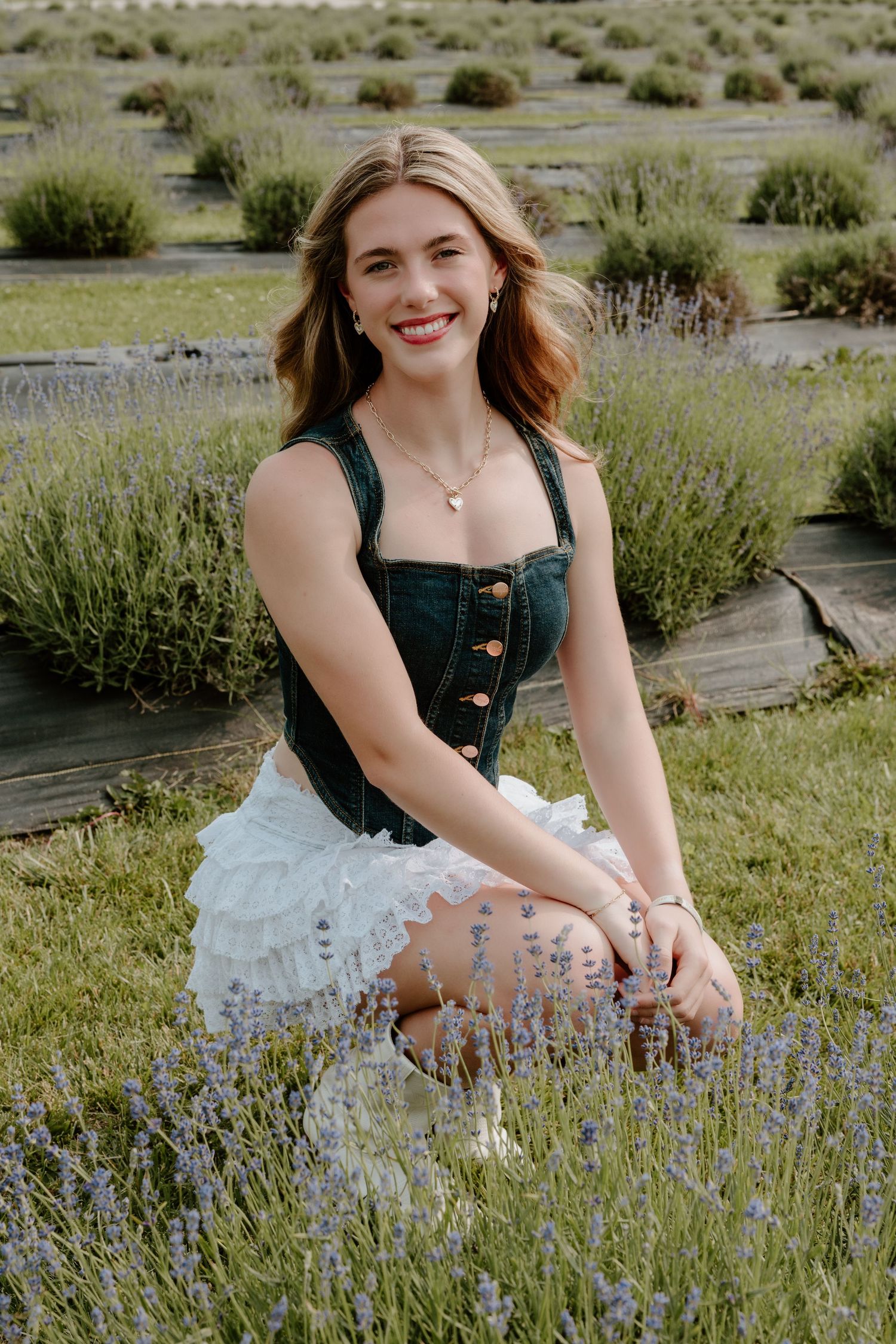 A summer portrait in a lavender field showing a stylish denim top and white ruffled skirt ensemble.