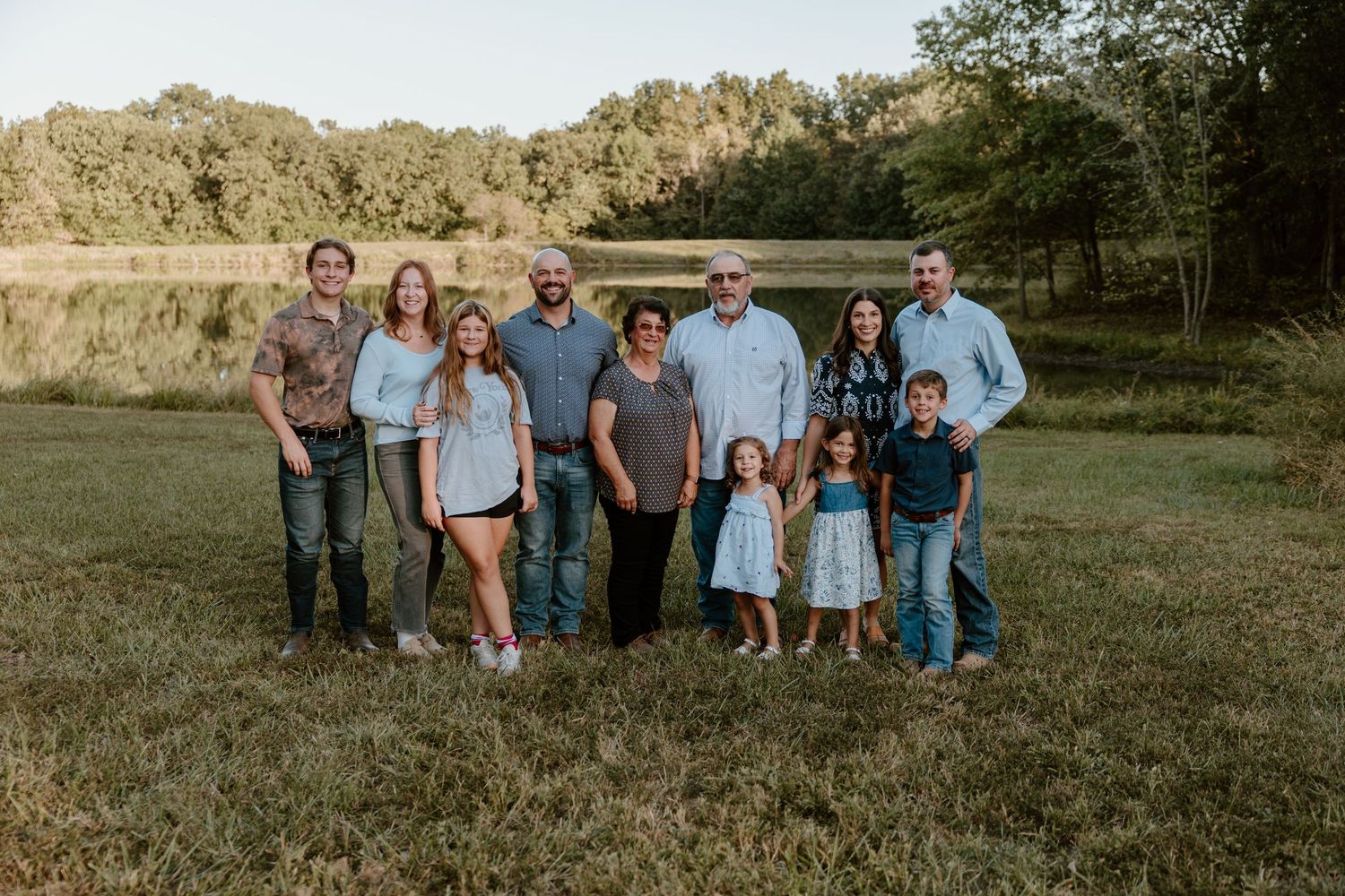 A group of people standing together in a grassy field during golden hour lighting.