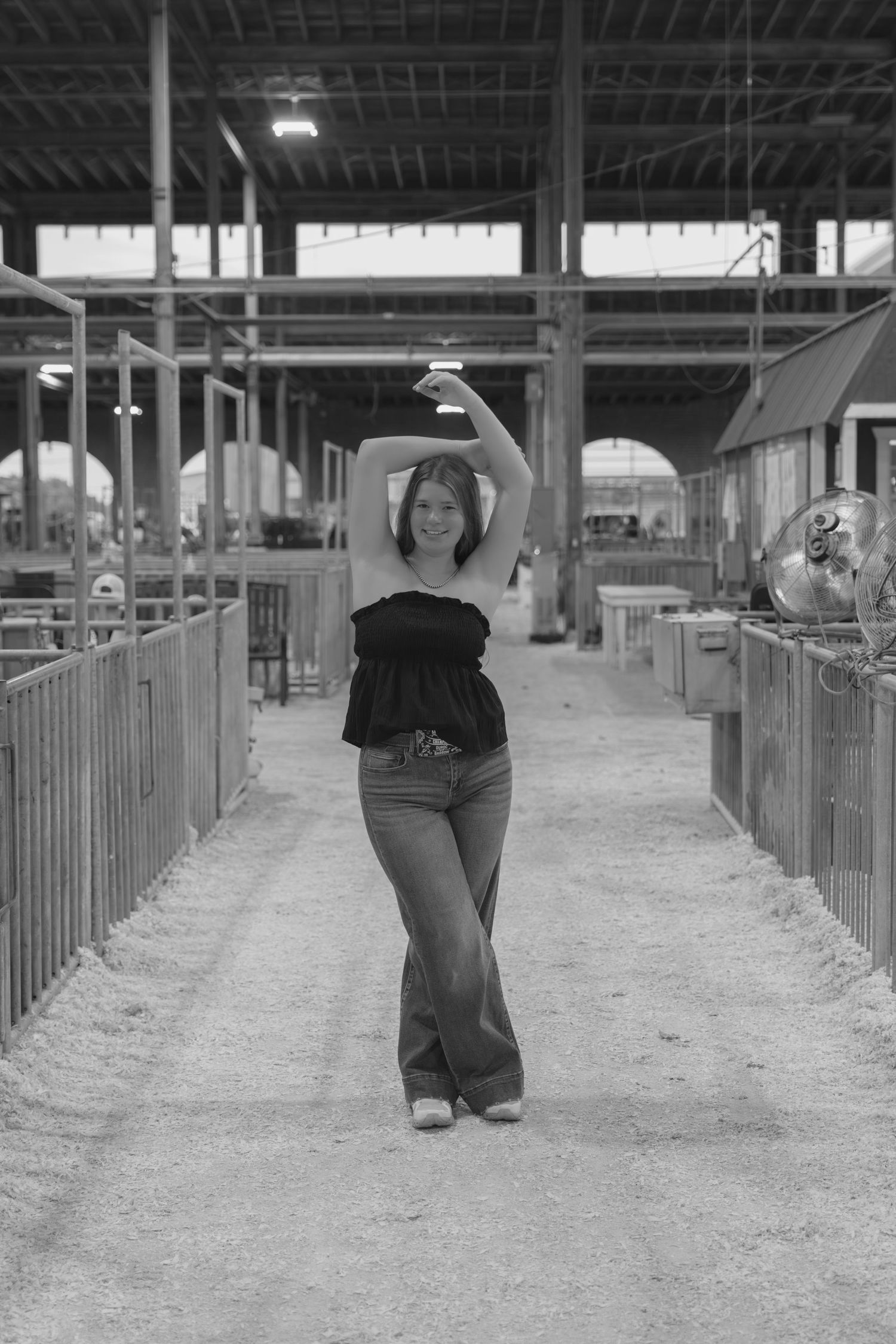 A series of photos showing someone posing playfully in a livestock barn with wooden stalls.