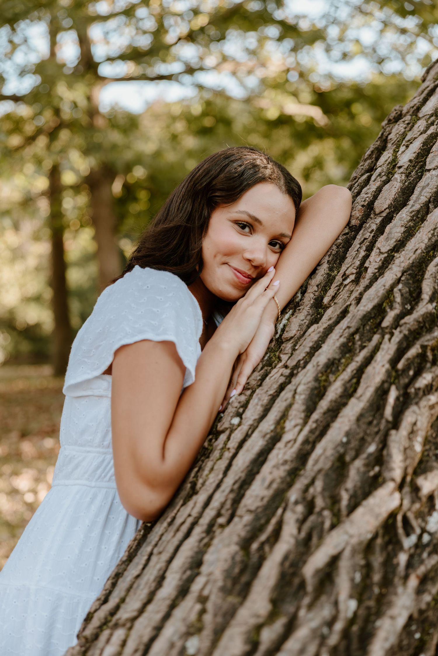 A series of artistic outdoor portraits showing someone in a white dress leaning against a textured tree trunk.