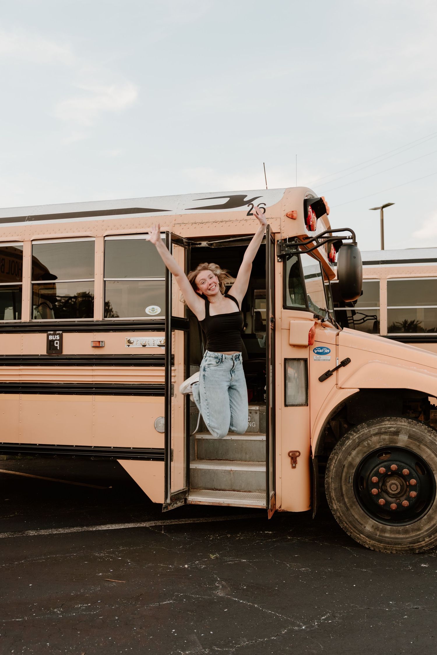 Four vintage beige school buses parked in a row on dark pavement showing different angles of their classic design.