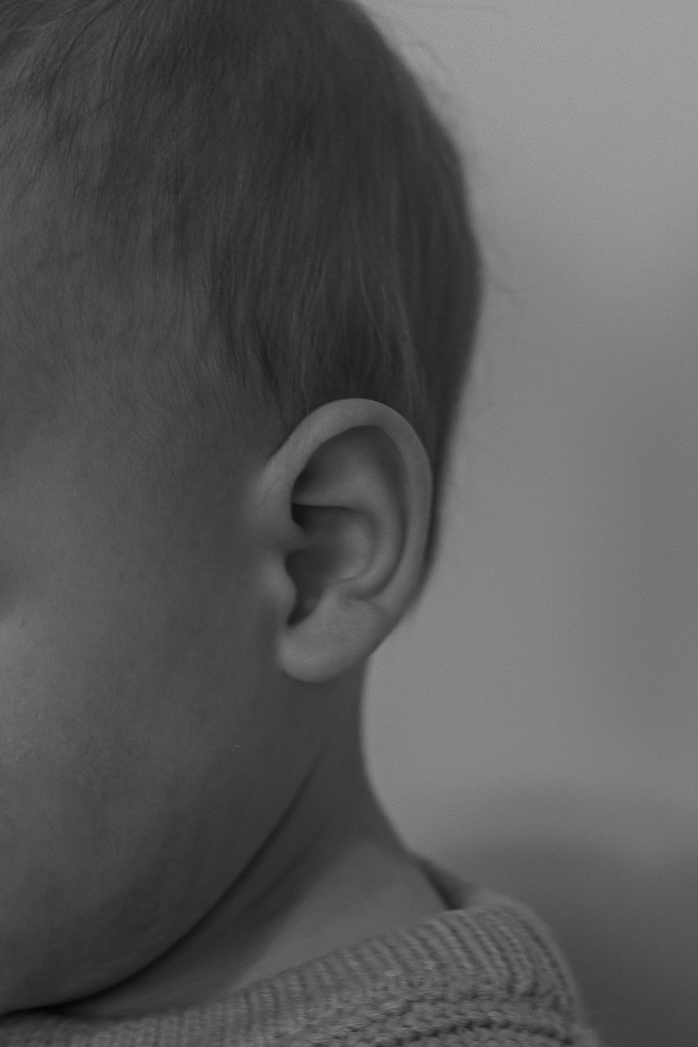 Close-up black and white profile shot of a baby's ear and head.