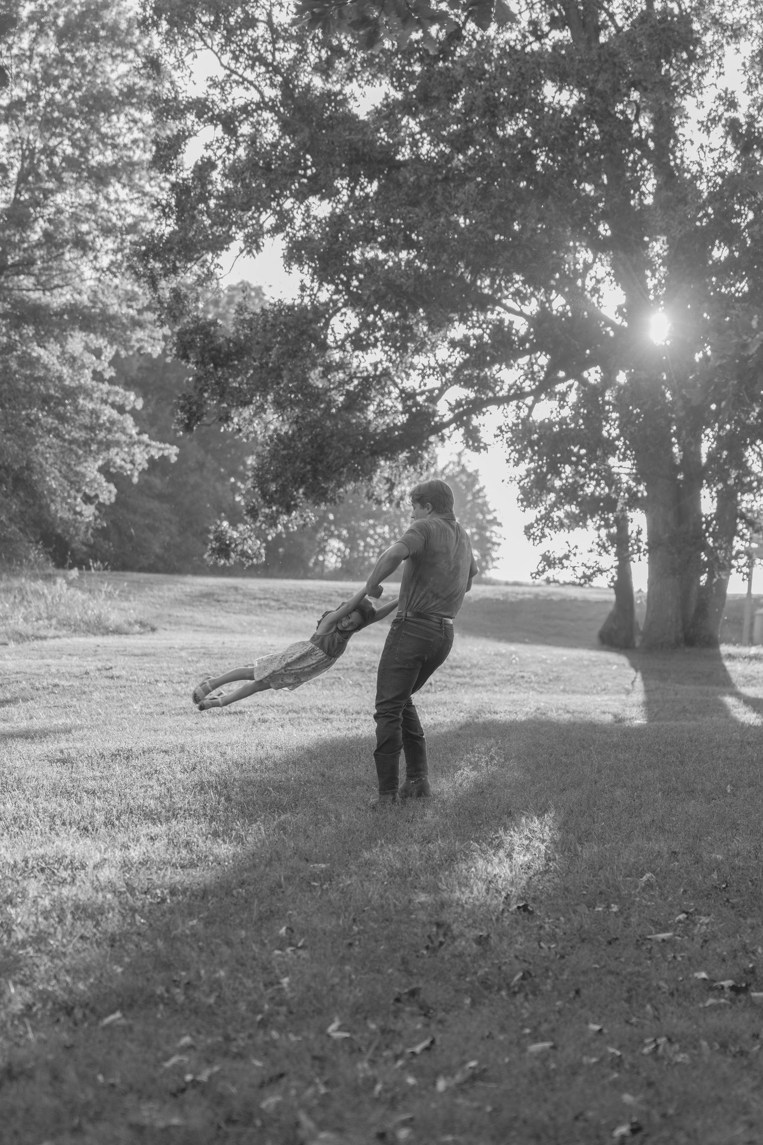 Black and white sequence showing a person falling down a grassy hill in a playful tumbling motion.