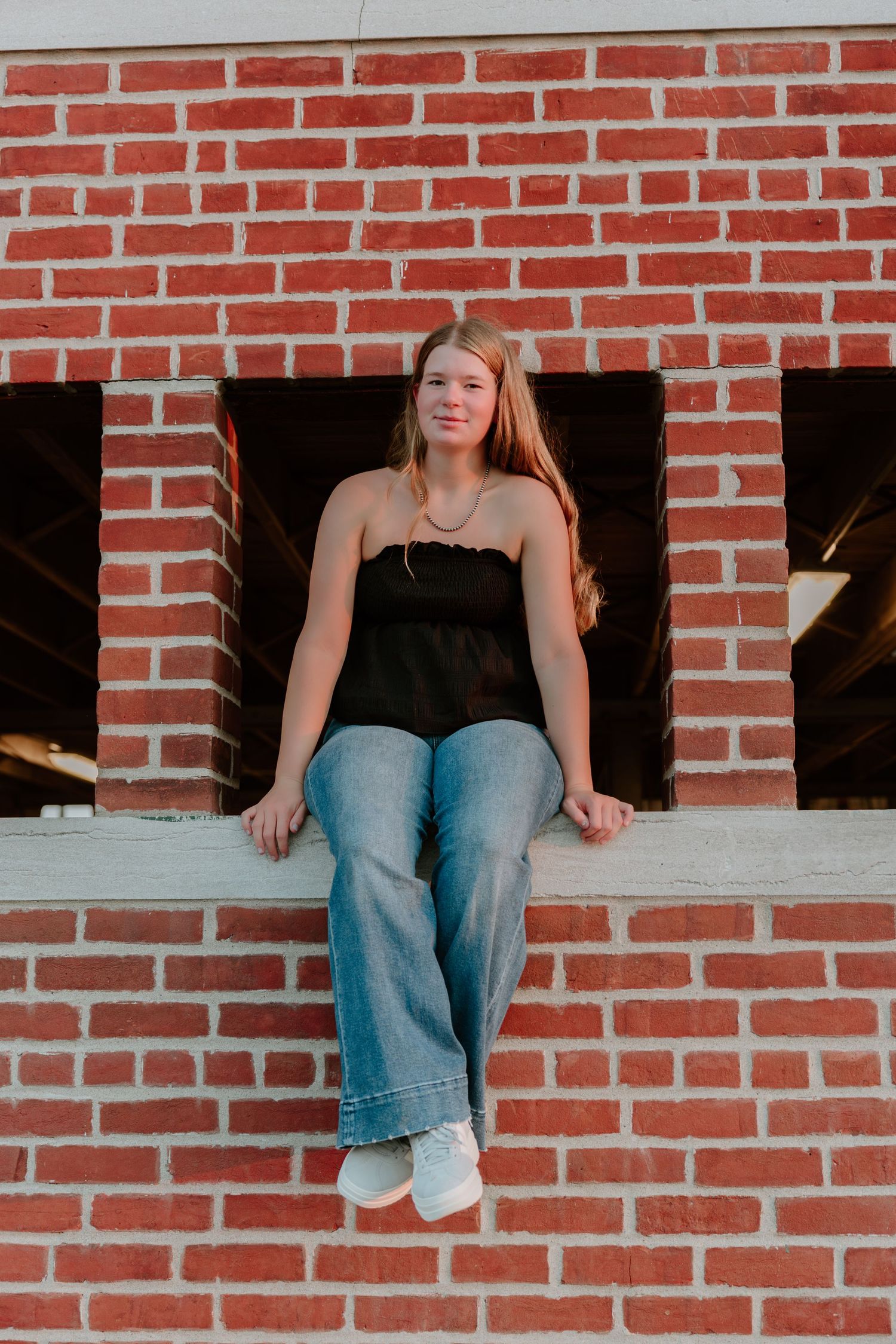 A series of cropped photos showing someone sitting on a brick wall wearing jeans and a black top.