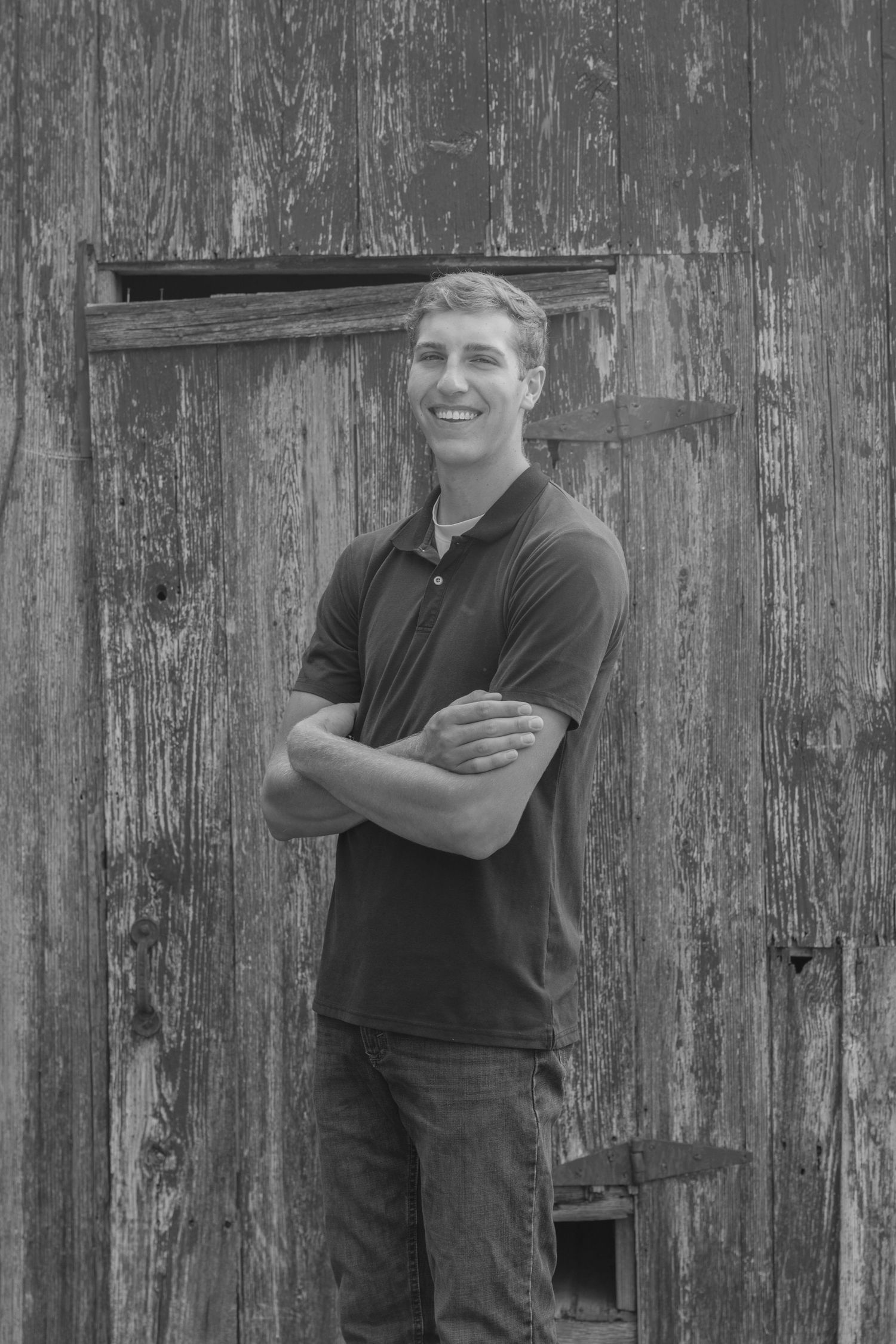 A series of four black and white portraits of a person posing against a weathered wooden barn wall.