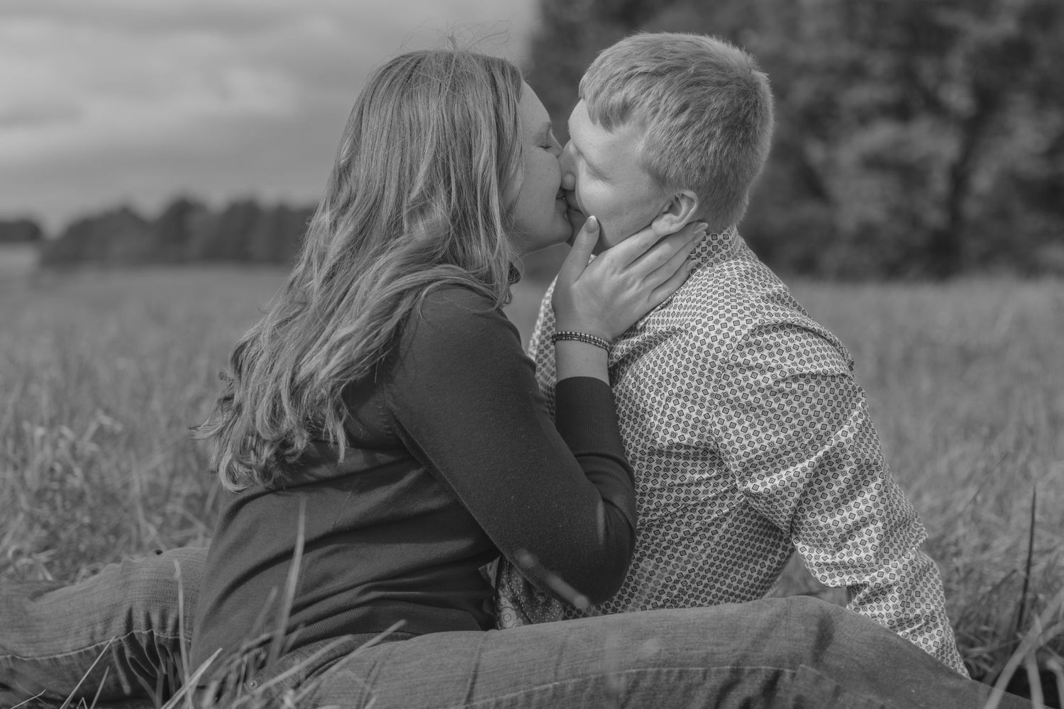 A romantic black and white photo series showing intimate moments between a couple in a meadow.