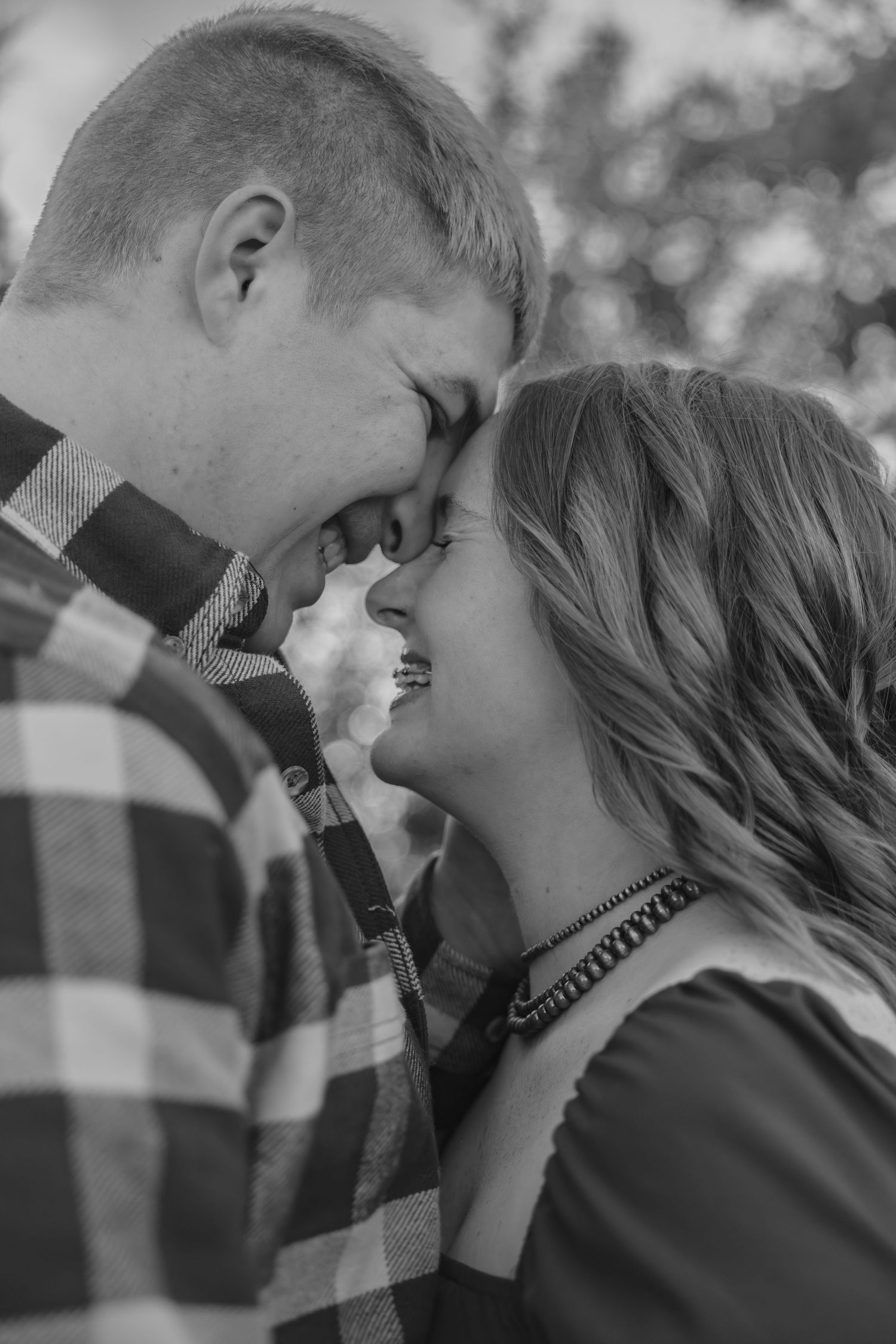 Black and white romantic portrait of a couple sharing an intimate moment in plaid shirt and casual wear.