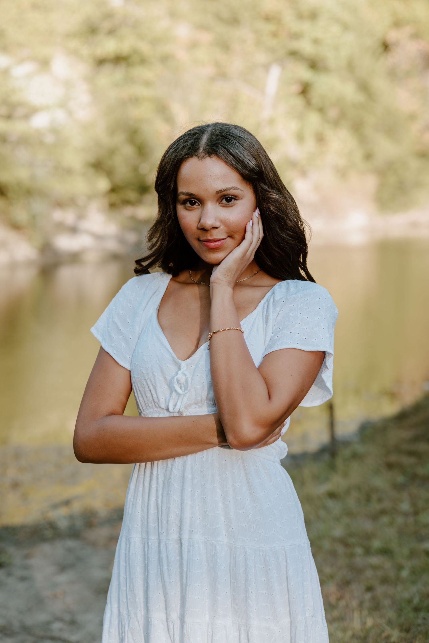 A series of outdoor portraits showing a person in a white dress posing playfully by a lake.
