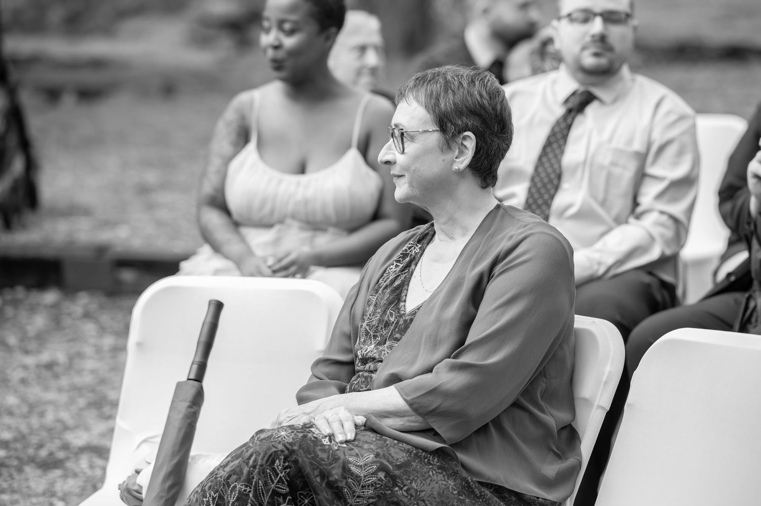 pensive candid black and white image of a female relative sitting in a folding chair watching the wedding ceremony at Valley Falls, WV