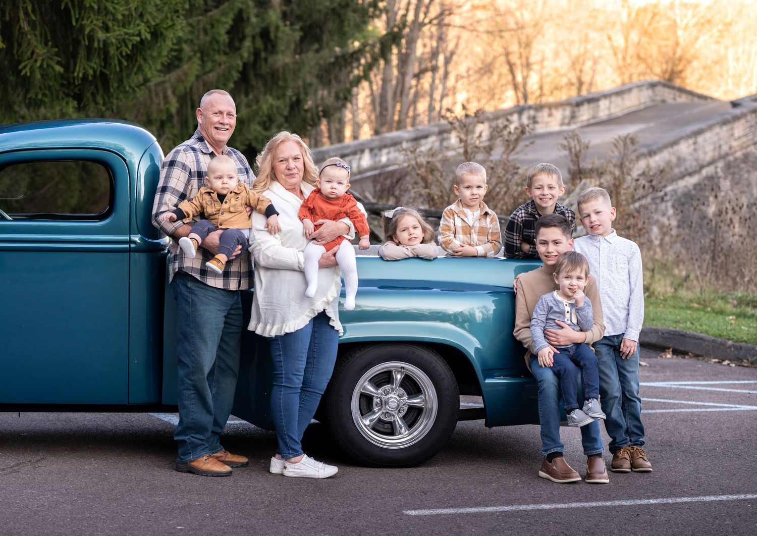 grandparents and their grandchildren pose for an extended family portrait with a classic model antique blue truck