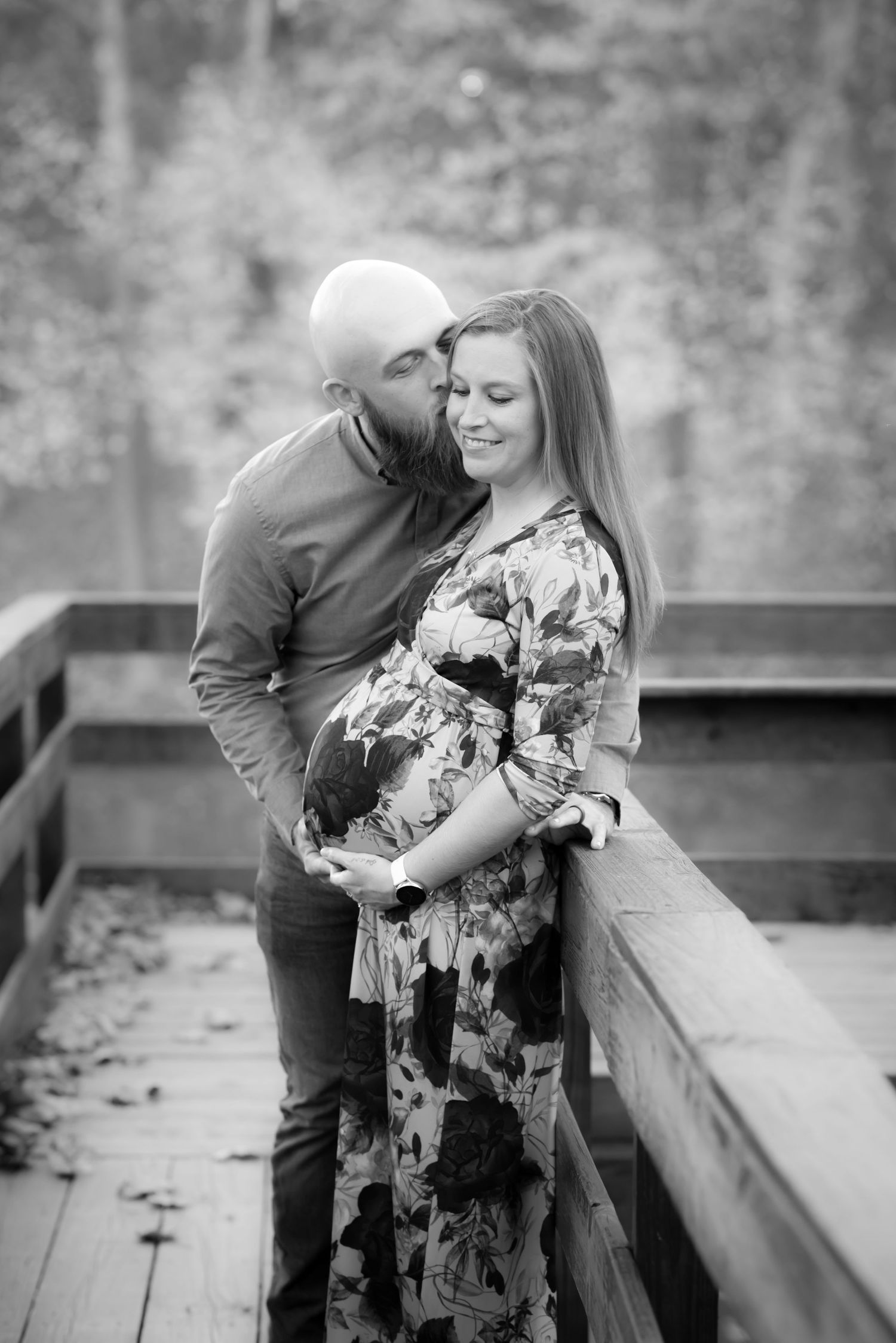 a young couple poses on a bridge for a maternity portrait
