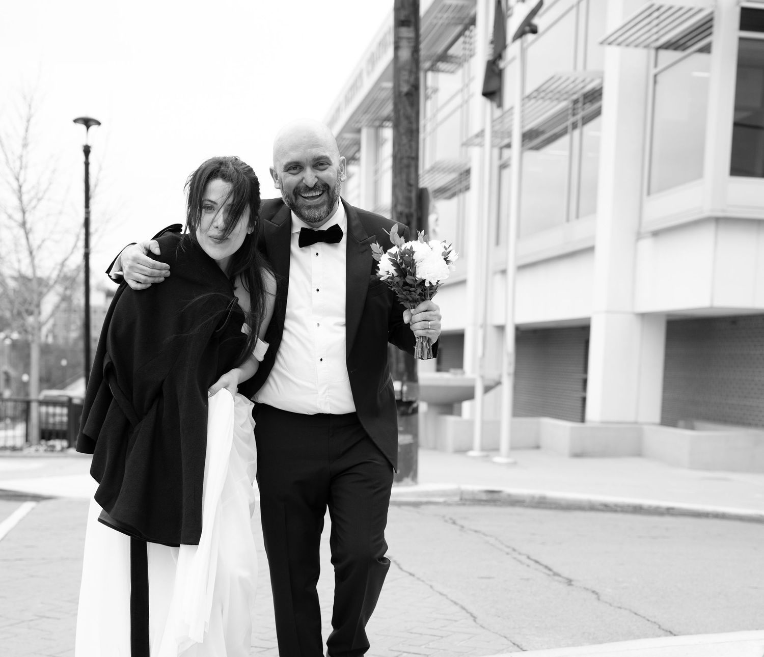 candid, styled black and white image of a bride and groom walking down the sidewalk after a courthouse wedding