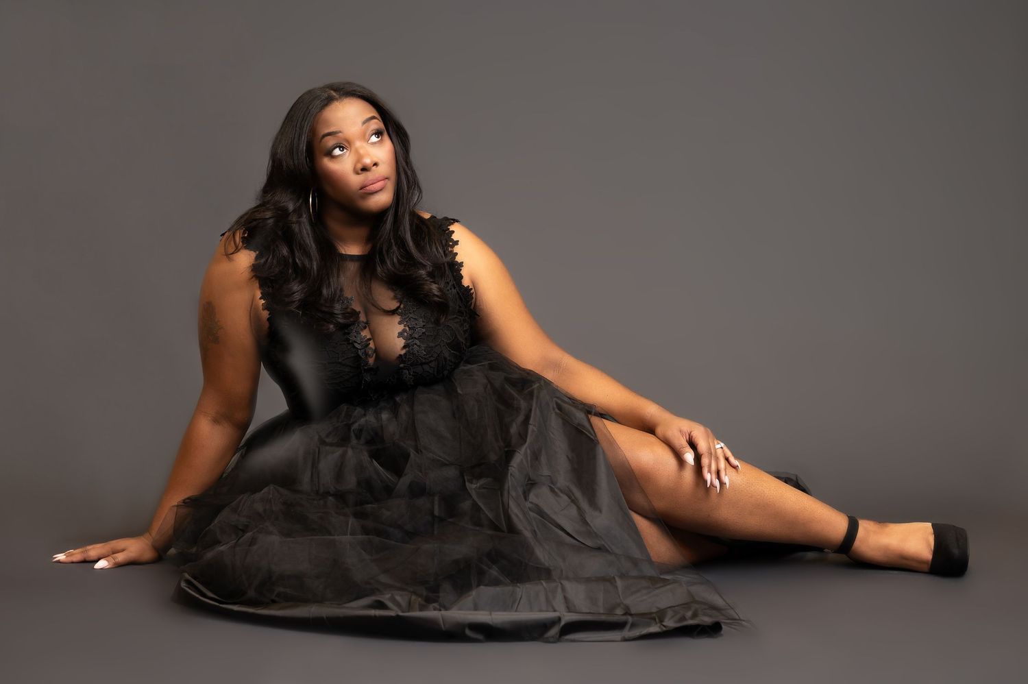 a lovely woman in a long elaborate black dress poses on a dark gray studio background for a portrait in Morgantown, WV