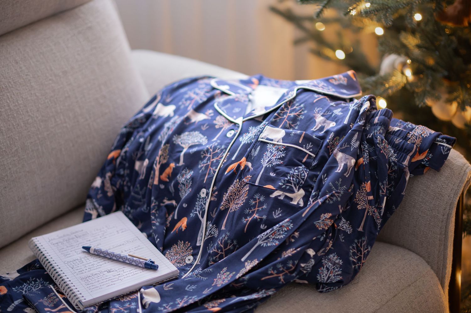 a pair of dark blue women's pajamas draped over a white chair, with a christmas tree in the background