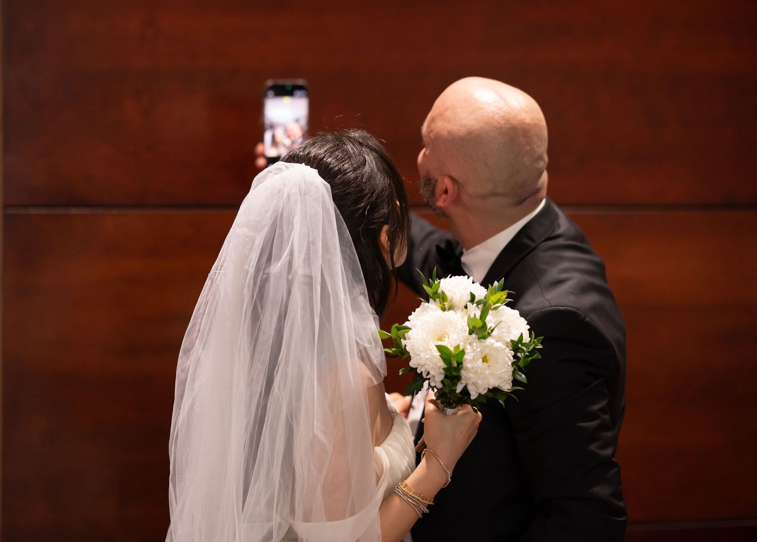 a bride and groom pose together and smile for a selfie