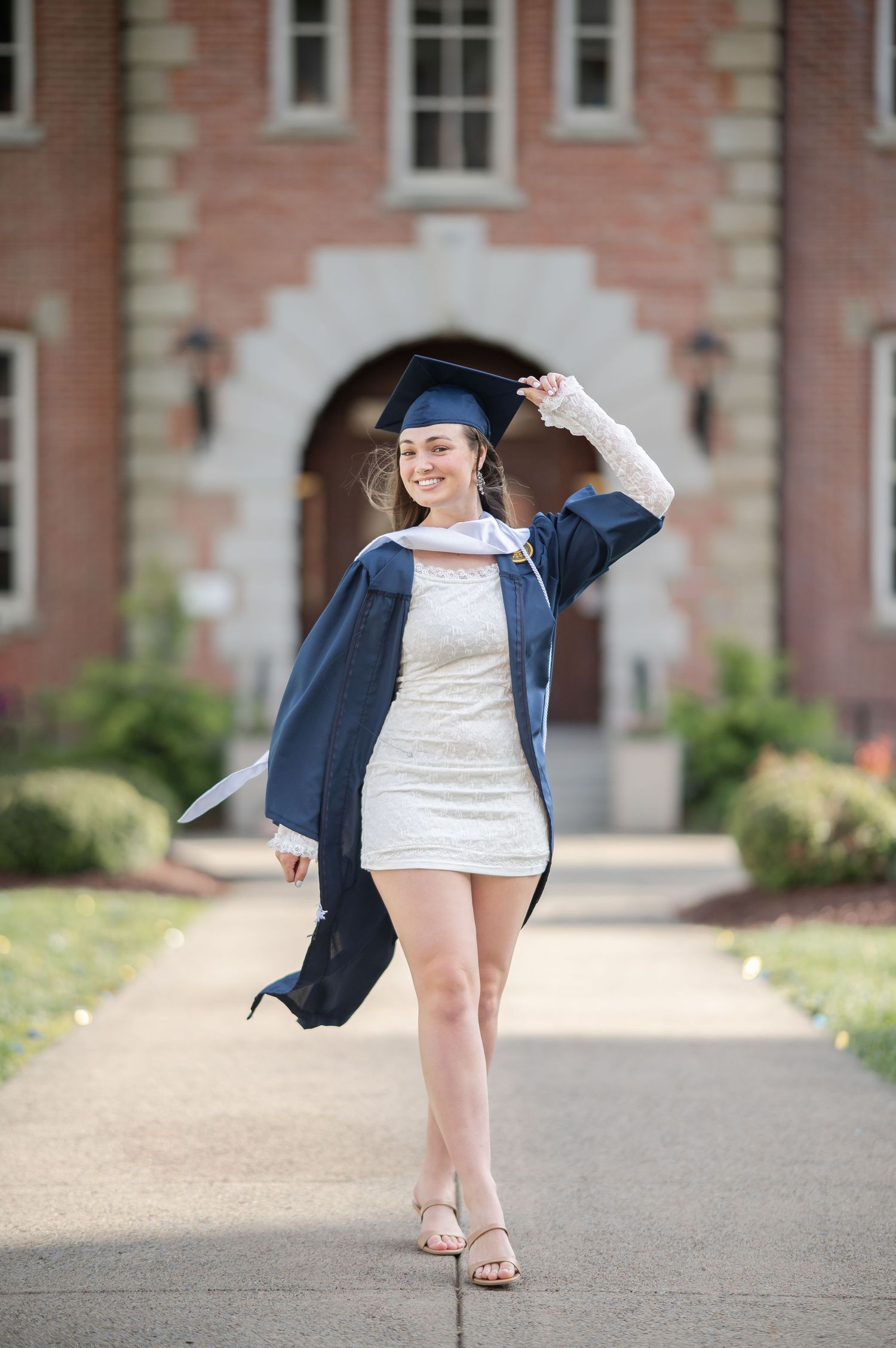 A graduating WVU senior in cap and gown walks down the sidewalk in Woodburn circle on WVU campus in Morgantown, WV