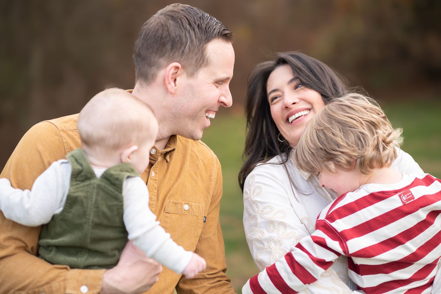 two parents laugh together while holding their young boys in their yard in Morgantown, WV