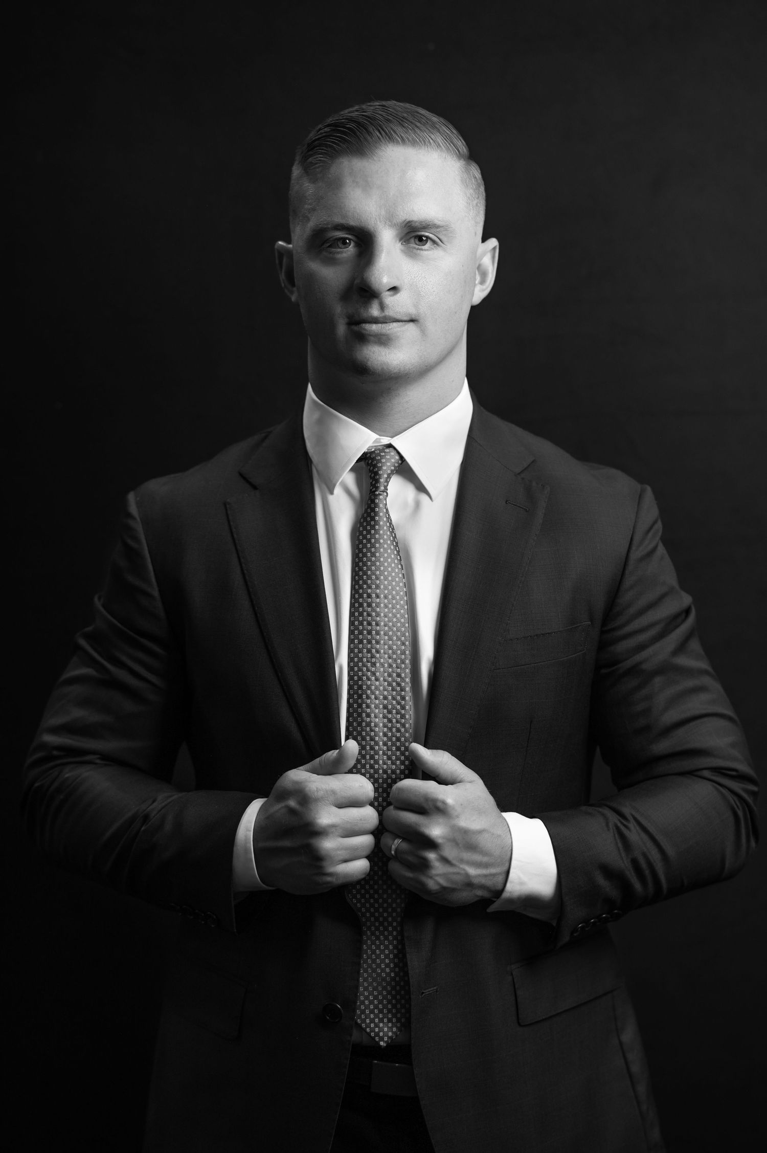 a bold, dramatic black and white headshot of a male lawyer in a suit against a black background; shot in Morgantown, WV