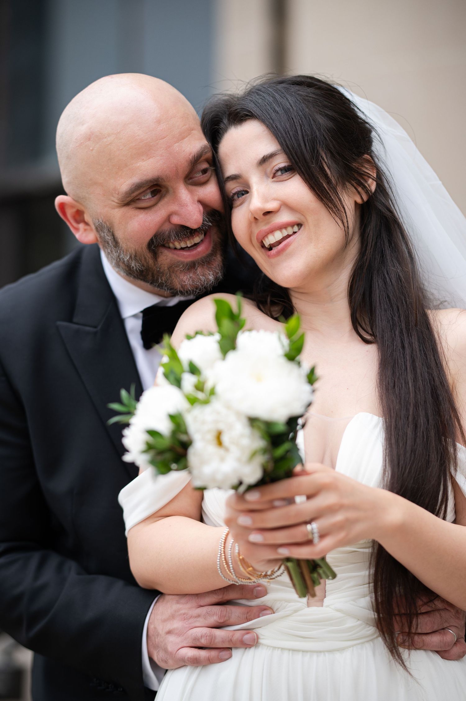 closeup portrait of a bride and groom cuddled together, smiling and laughing; downtown Morgantown, WV
