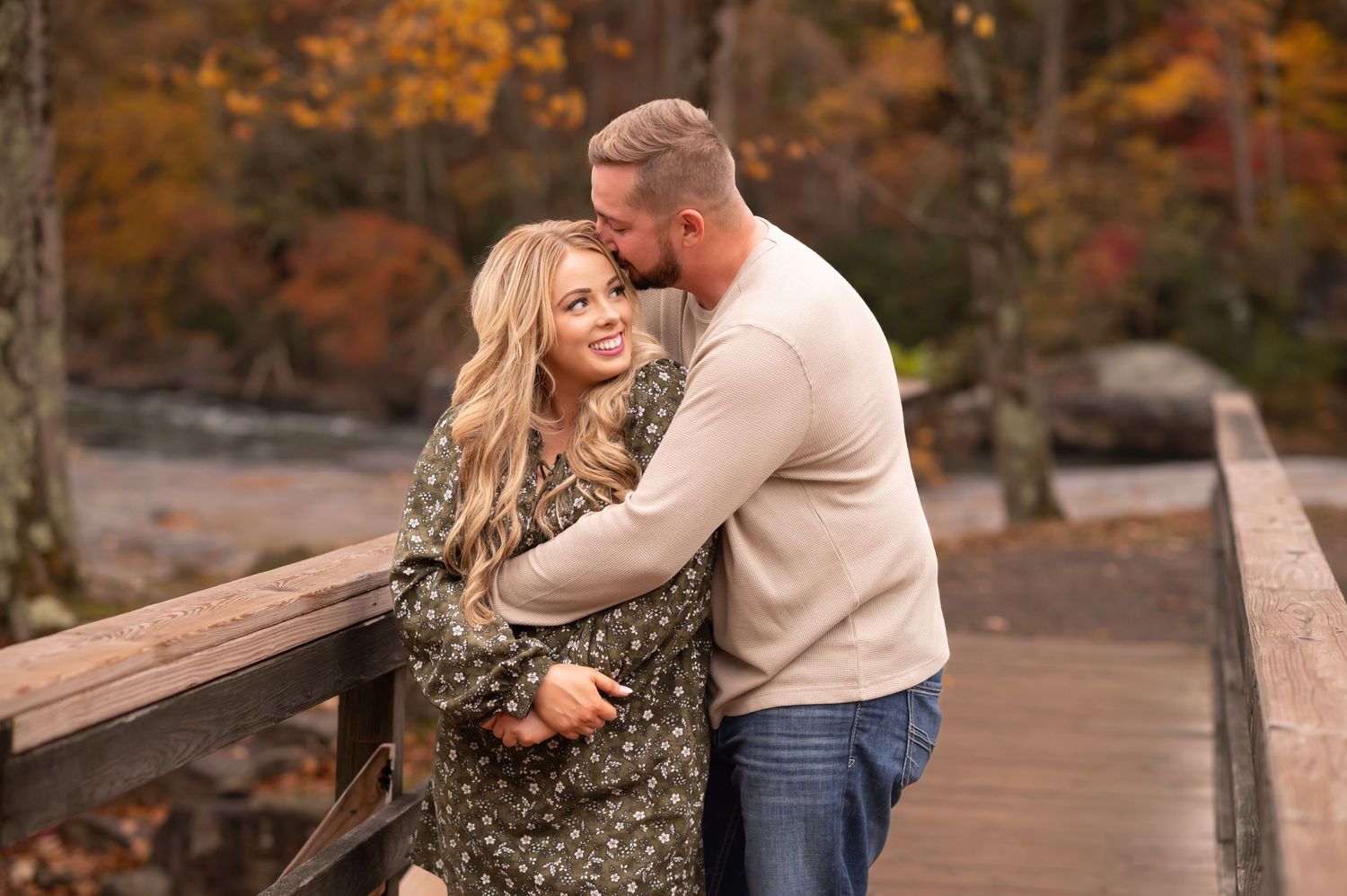 portrait of a young couple posing on a wood bridge in front of a waterfall in Valley Falls, WV