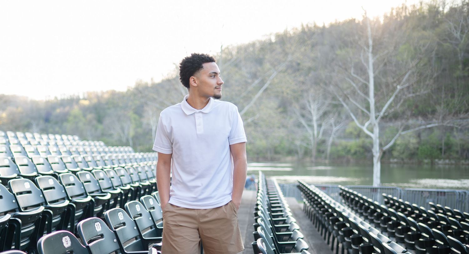 a graduate student in a white polo and khakis walks between stadium seats at the Hazel Ruby McQuain amphitheater in downtown Morgantown