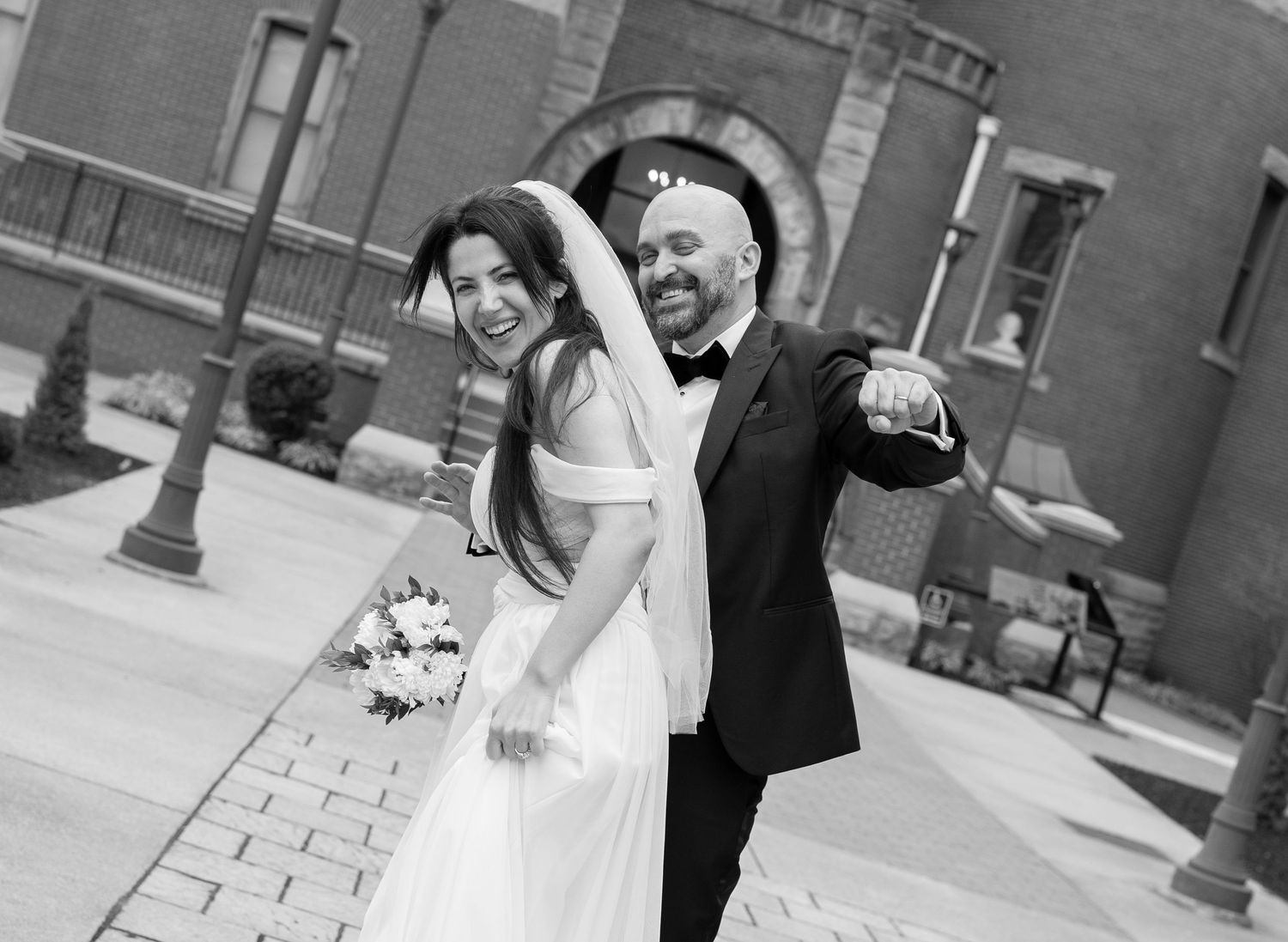 black and white candid portrait of a bride and groom laughing and dancing in front of the courthouse in Morgantown, WV