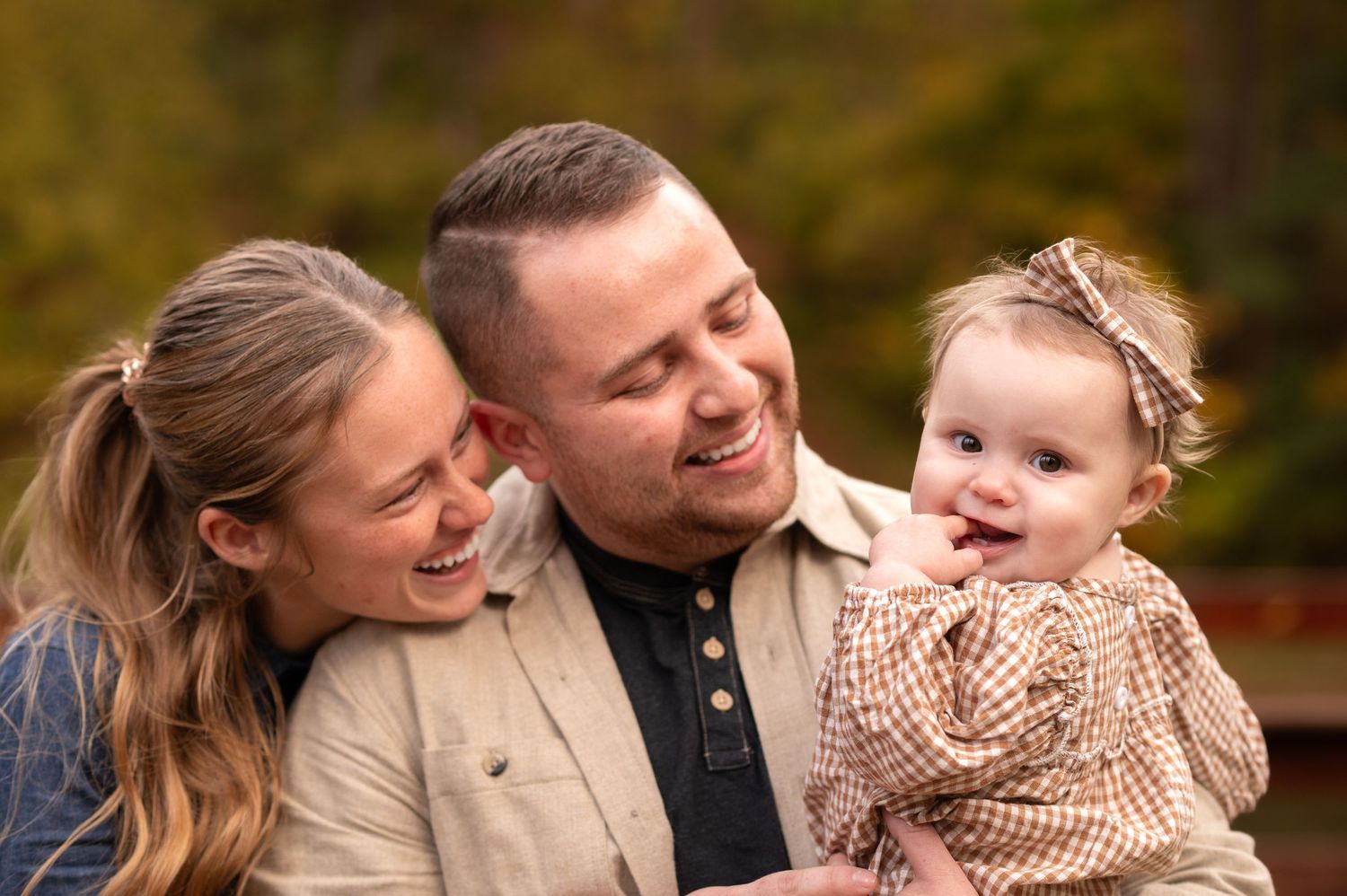 candid portrait of a young couple playing with their toddler daughter outside in the fall
