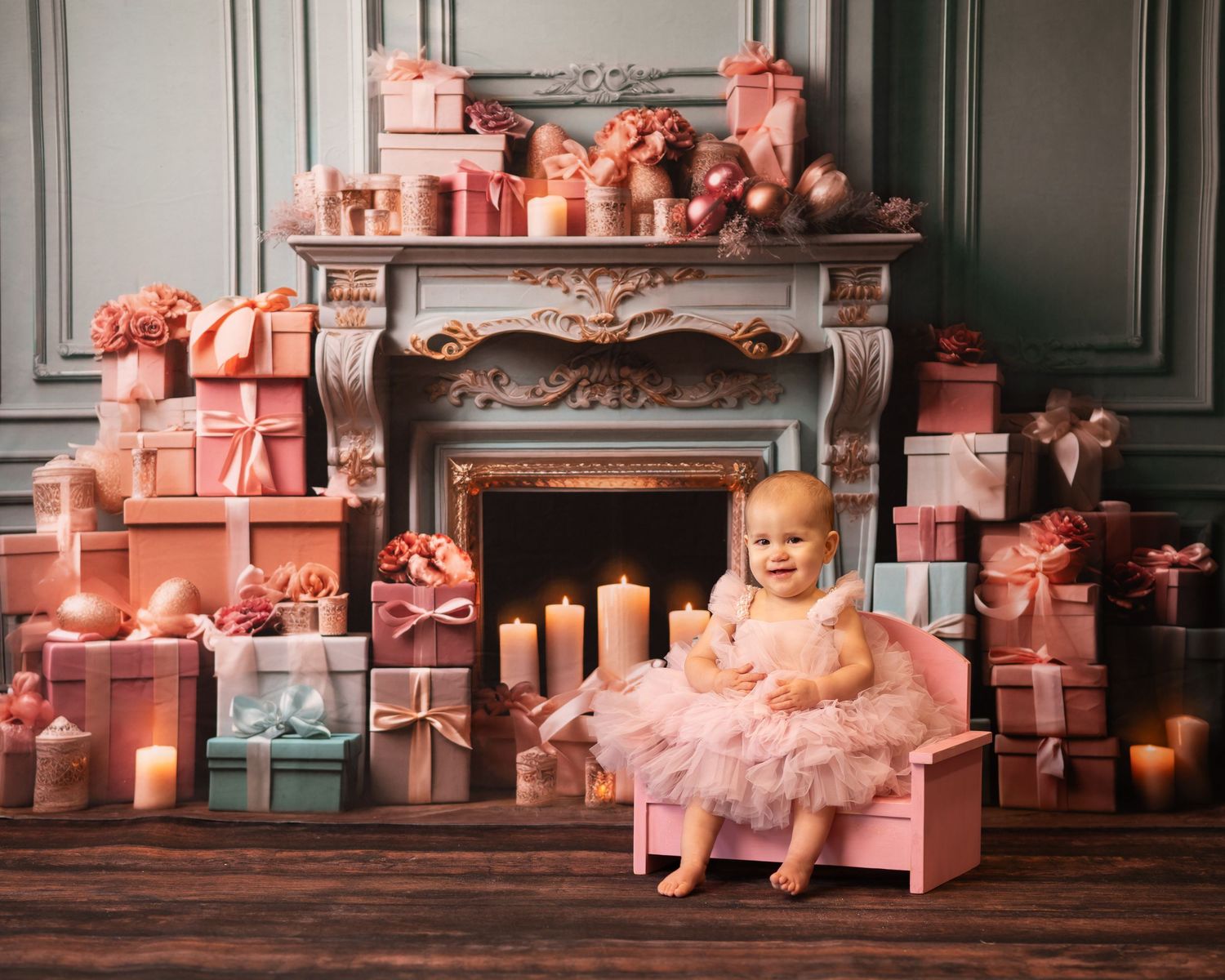 Christmas studio portrait of a baby girl in a fluffy pink dress, sitting in a pink chair in front of a fireplace surrounded by wrapped gifts