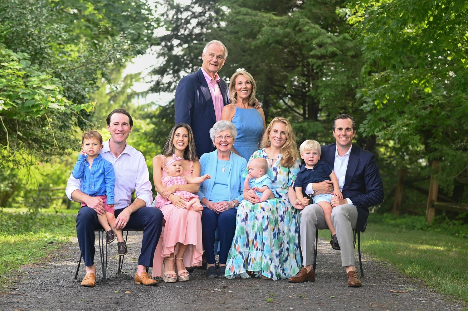 an extended family portrait posed on an old country gravel road with trees and grass all around