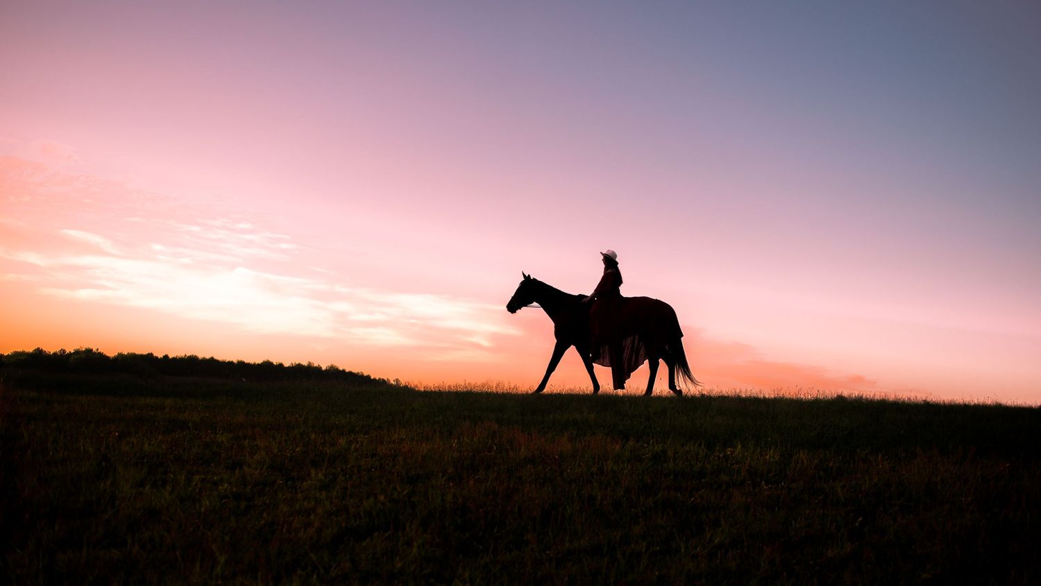 silhouette portrait of a young woman in a long dress, riding her horse across a ridge with the sunset behind them