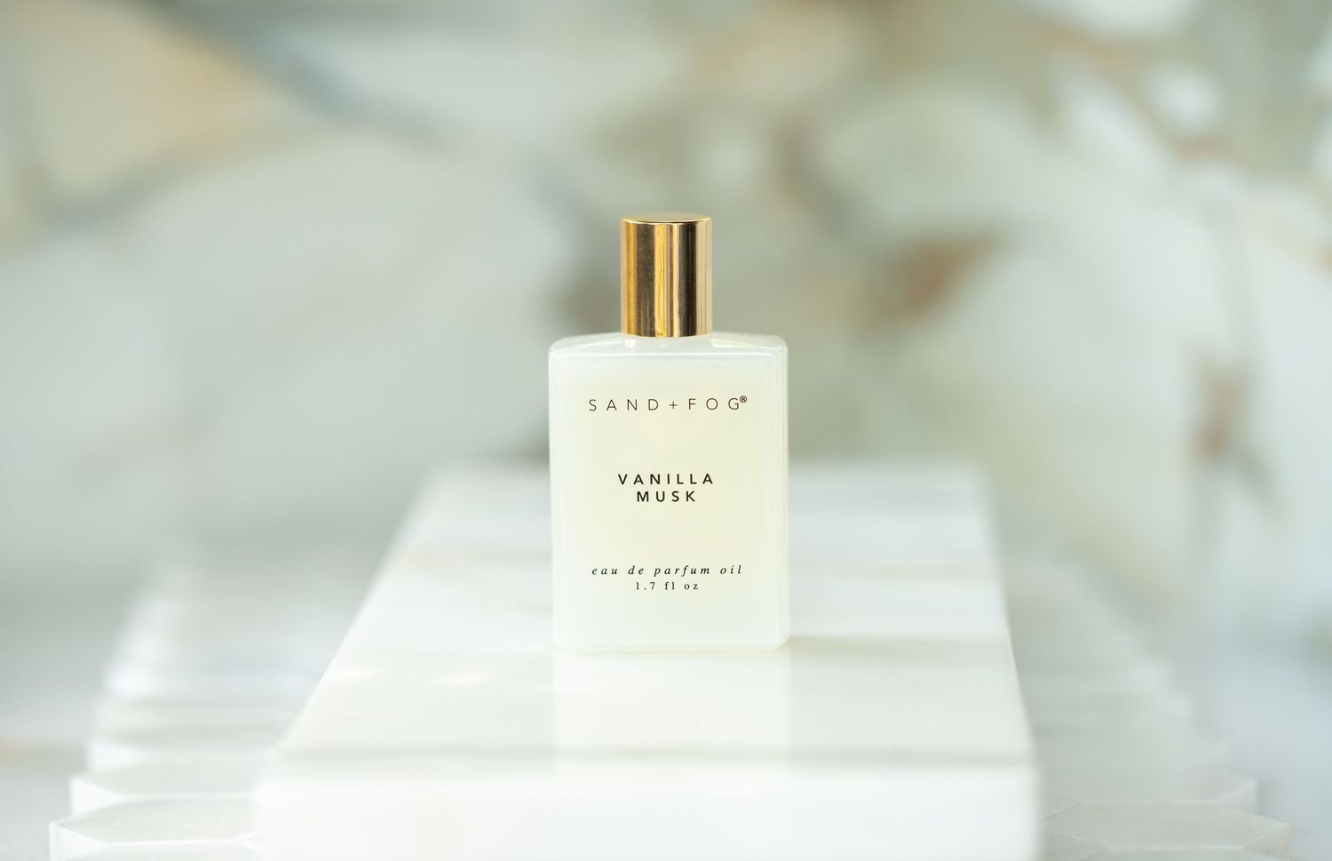 product image of a bottle of white perfume on a marble tray with marble walls in the background