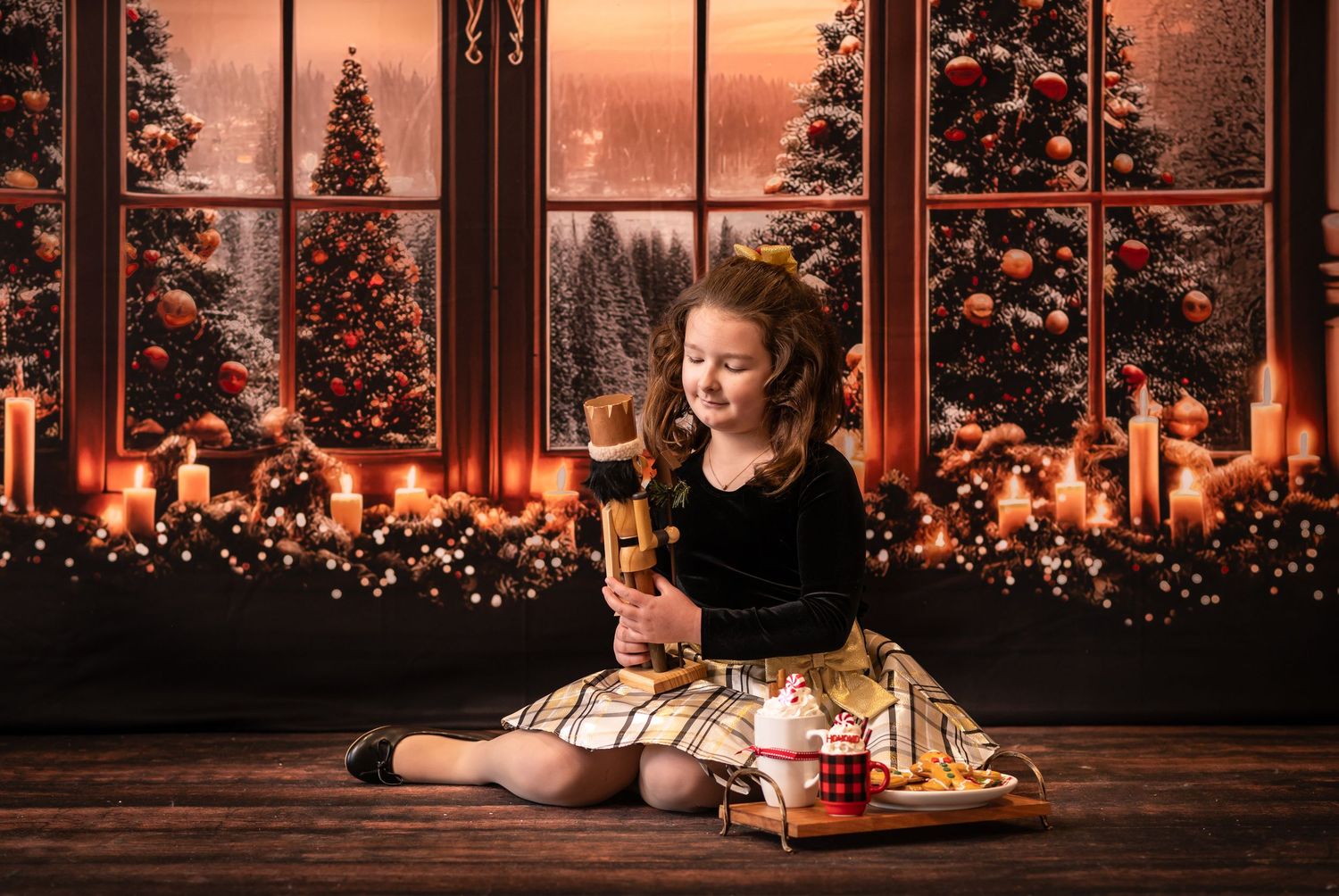 a little girl in a gold and black dress sits on a wood floor and poses for a christmas portrait with a vintage nutcracker and hot cocoa