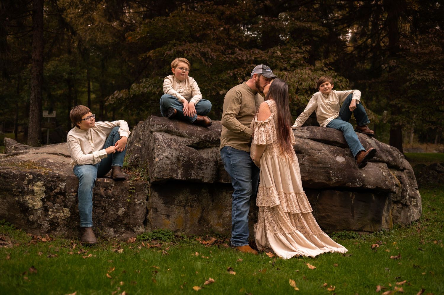a pregnant woman in a long lace dress strikes a dramatic pose with her husband and three sons, on a large rock at Valley Falls, WV