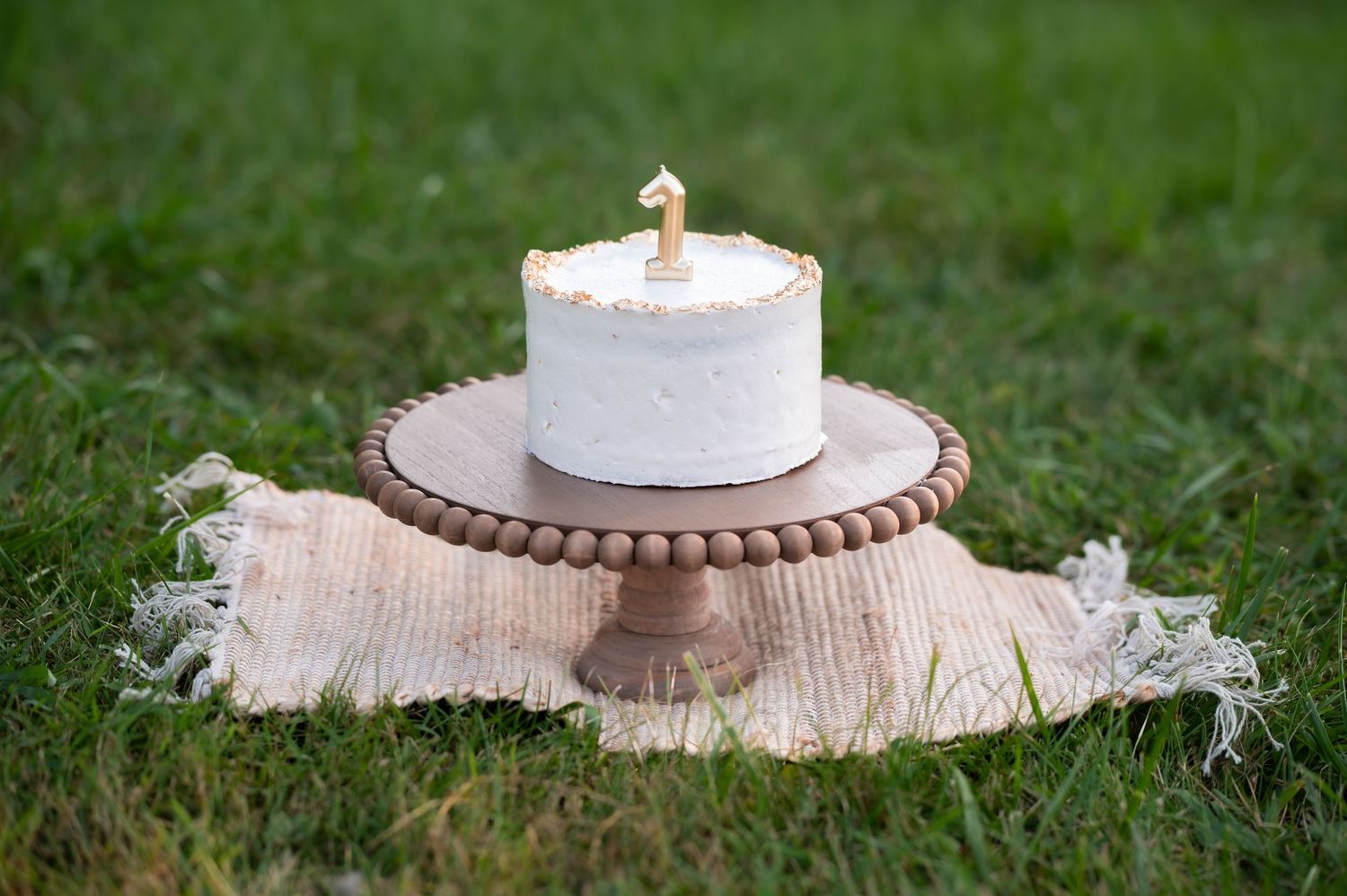 a little white smash cake with metallic gold trim and a gold 
