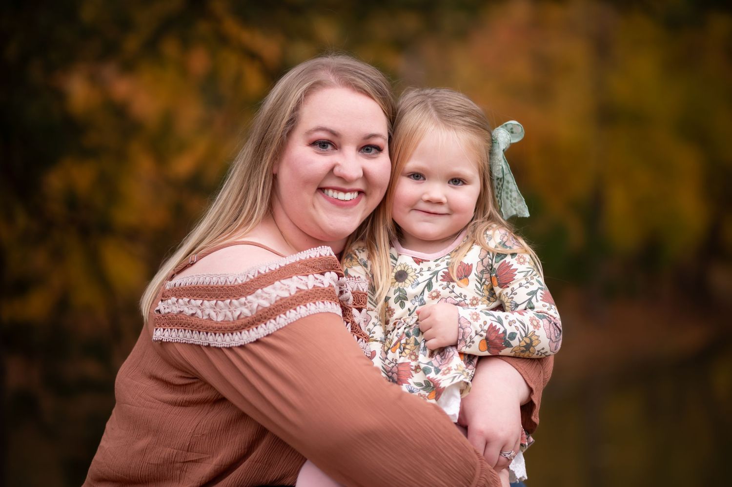 a young mother poses with her toddler daughter amid brilliant outdoor fall scenery in Westover, WV.