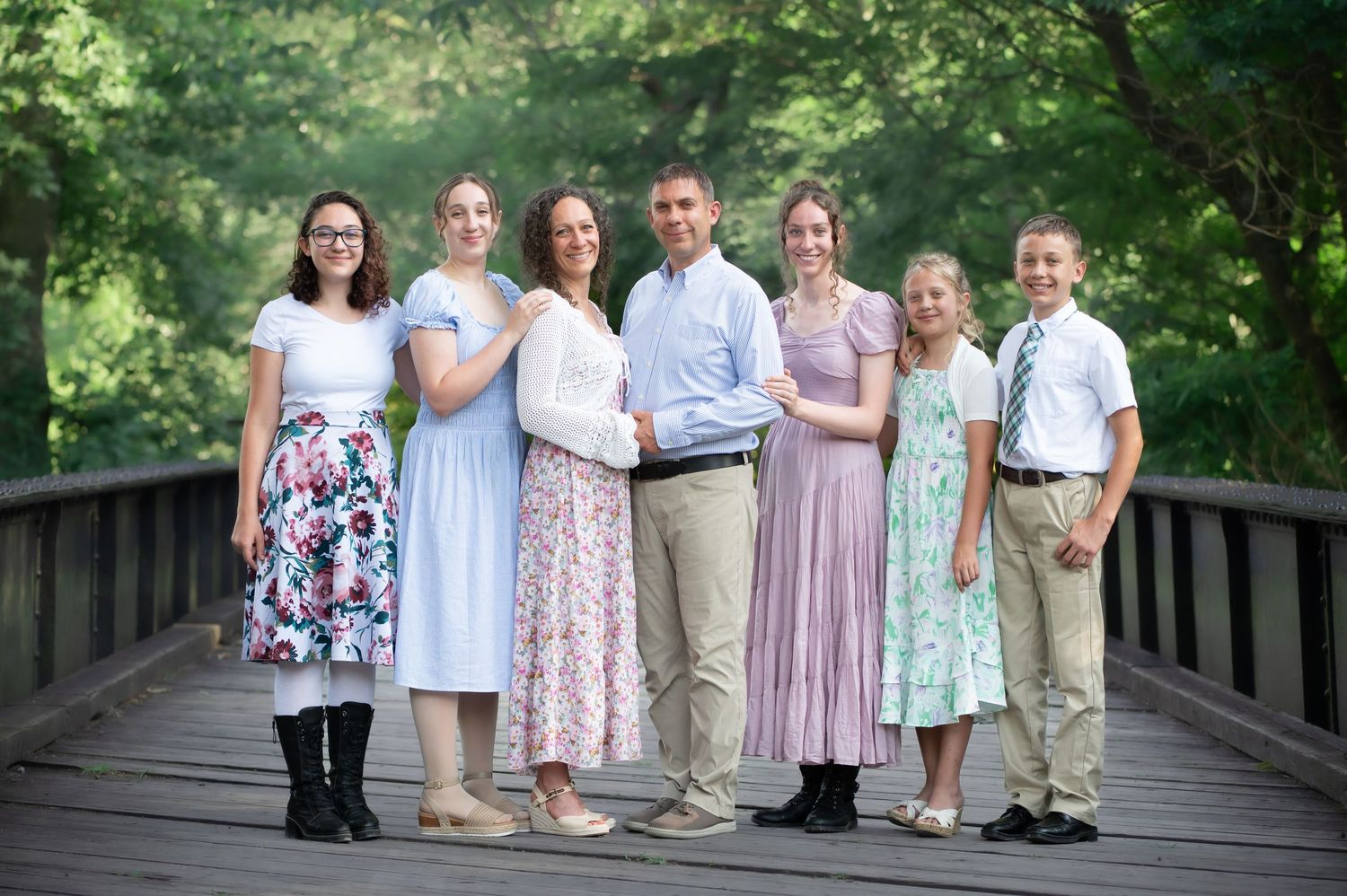 a family of seven poses for a portrait on an old wooden and metal railroad bridge in Valley Falls State Park, WV